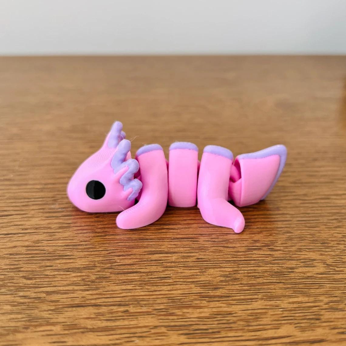 Adorable articulated axolotl in vibrant pink with purple accents, perfect for sensory play and stress relief.