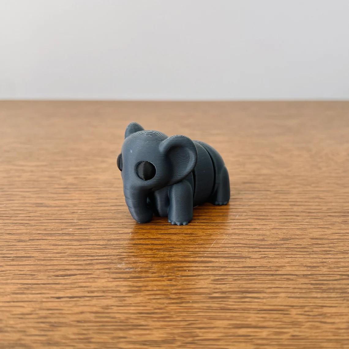 Charming dark grey elephant with articulated features, perfect for sensory play, set on a wooden surface.