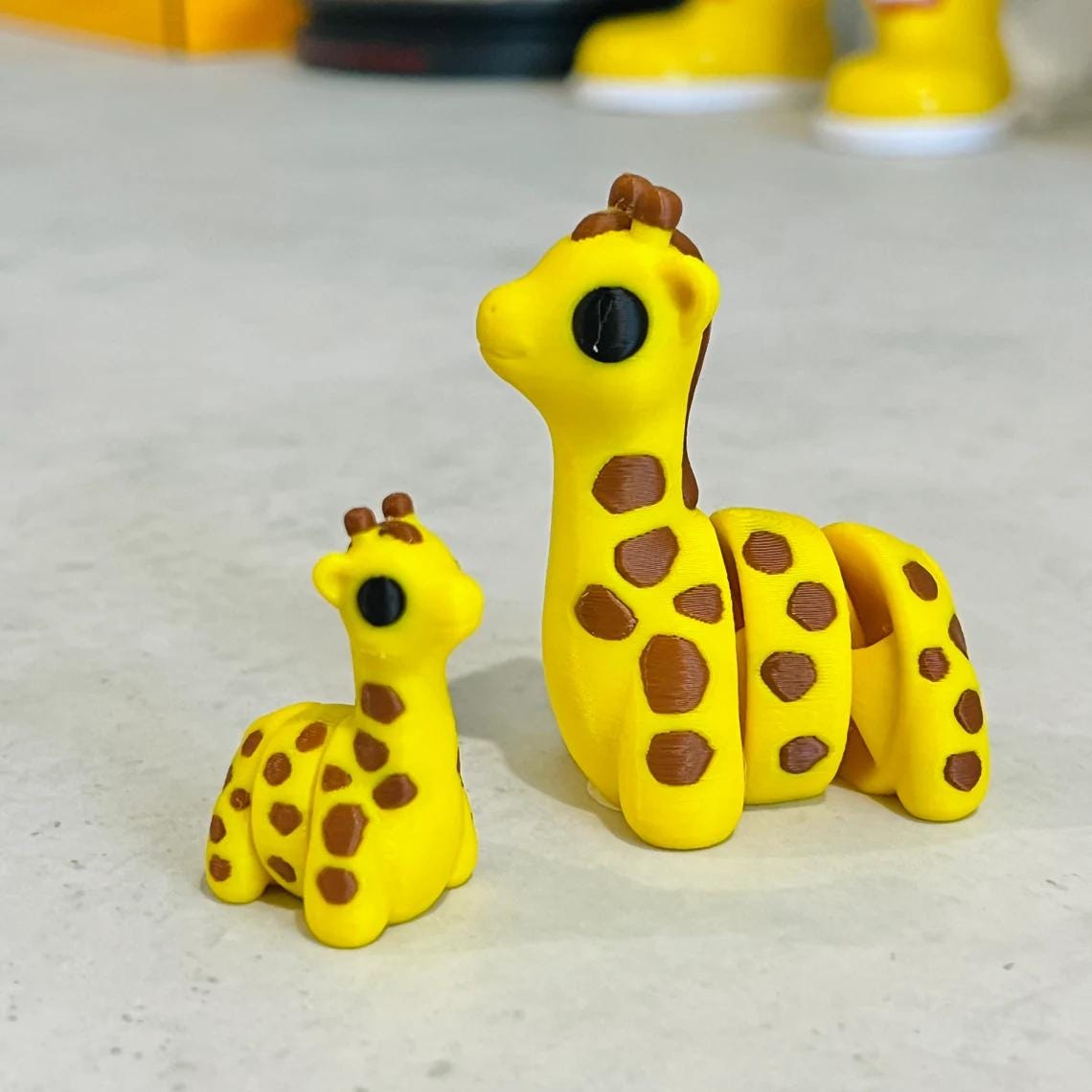 Two adorable articulated giraffes in yellow with brown spots, showcasing charming details for sensory play and collection.