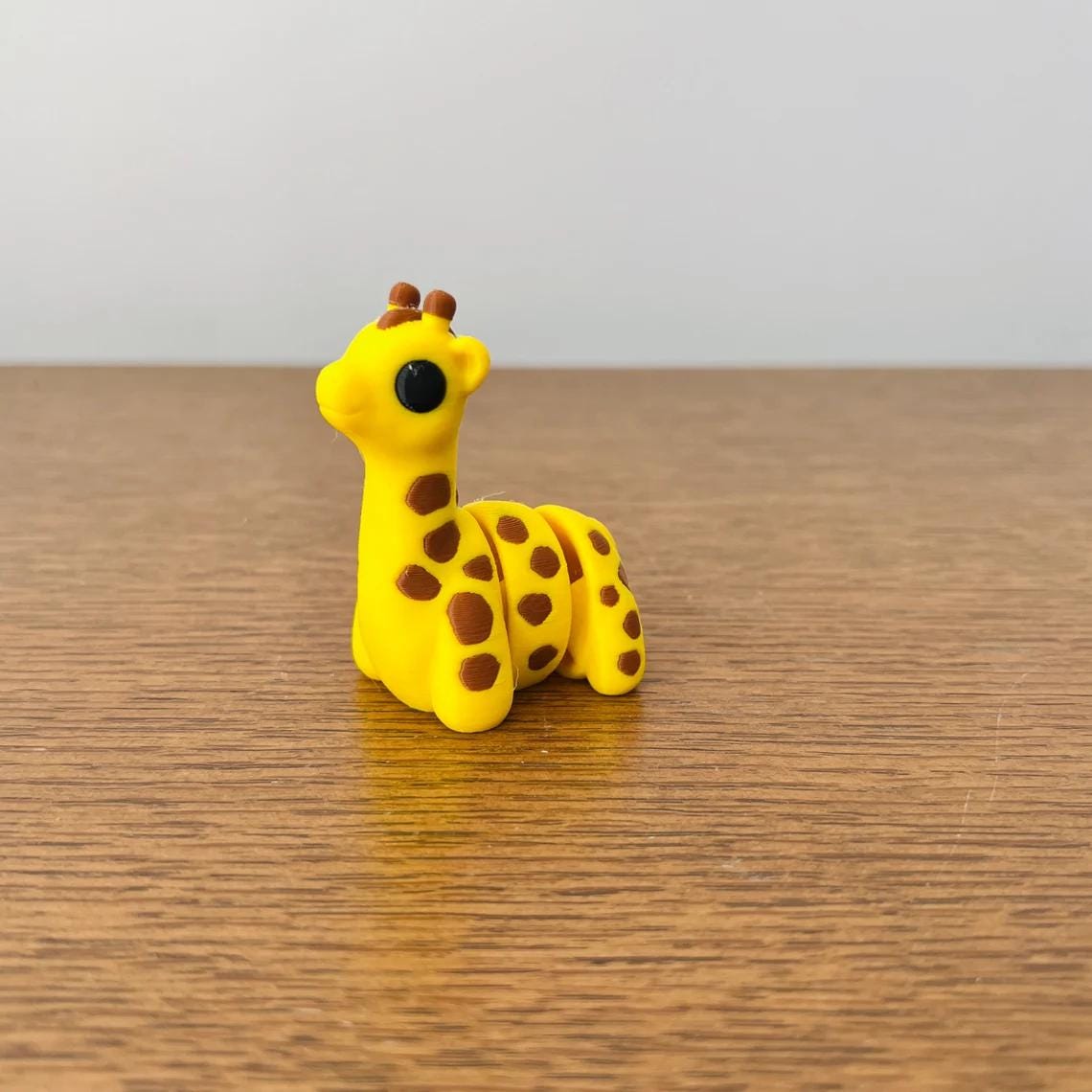 Adorable mini giraffe in bright yellow with brown spots, perfect for sensory play and stress relief. Eco-friendly material.