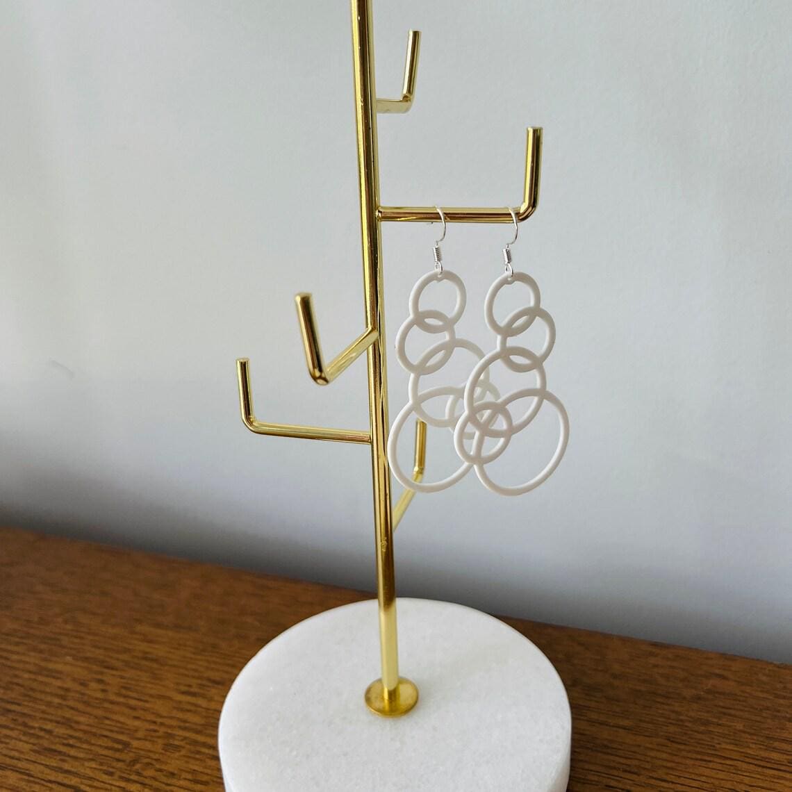 White bubble dangle earrings hang from sterling silver hooks, showcasing a playful, modern design on a display stand.
