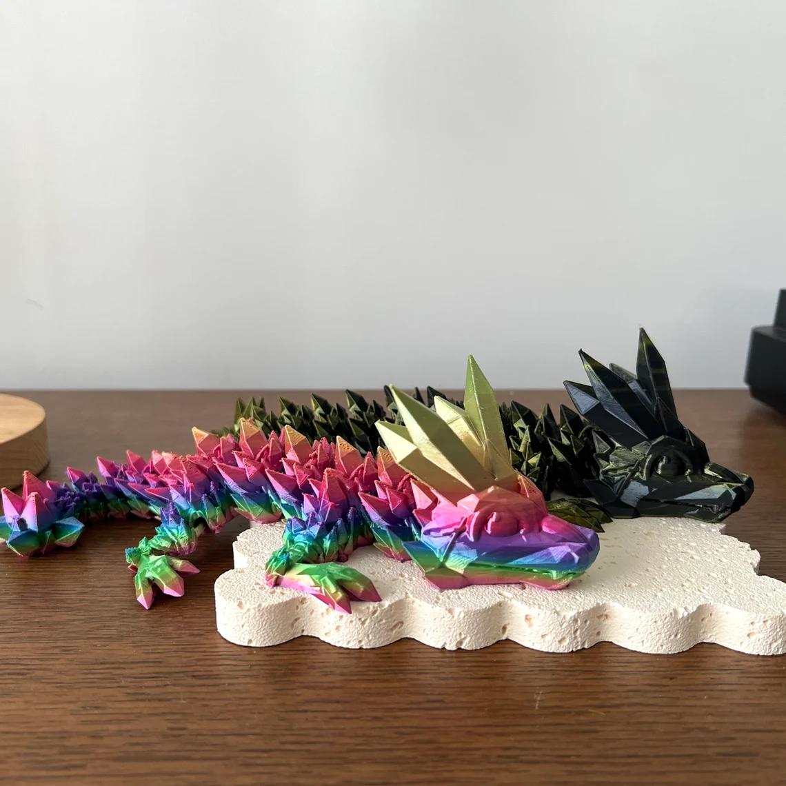 Colorful 3D printed dragon figurine with vibrant scales and striking golden spikes, resting on a textured base.