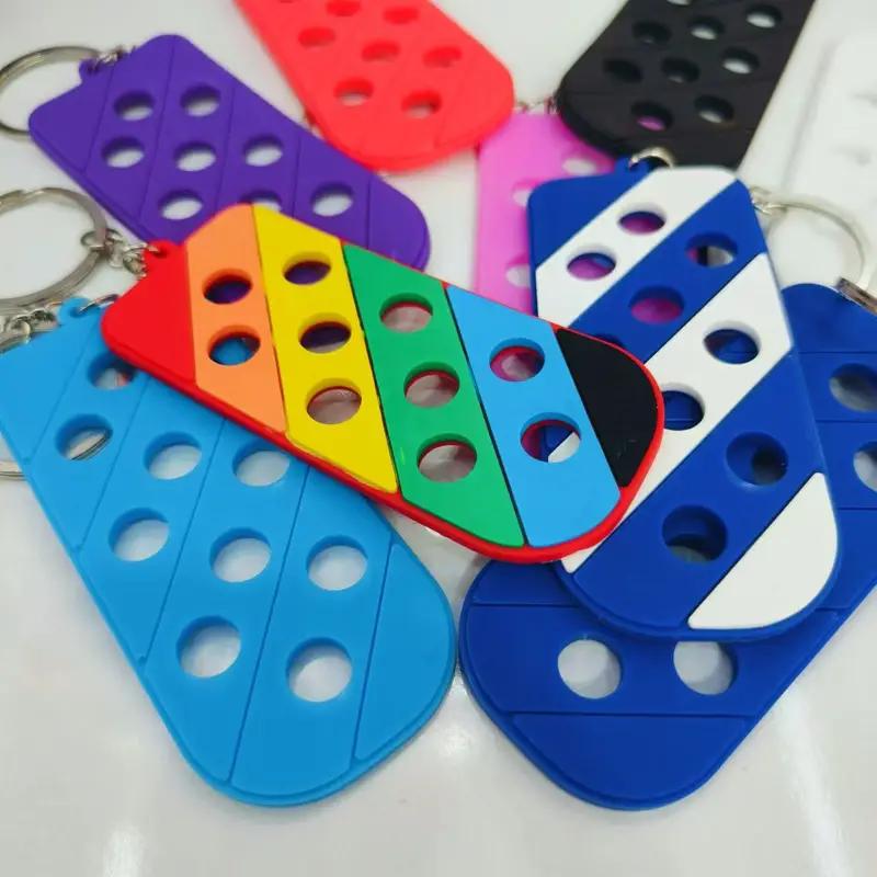 Colorful keychains in various shapes and hues, featuring holes for attaching charms, creating a playful display.