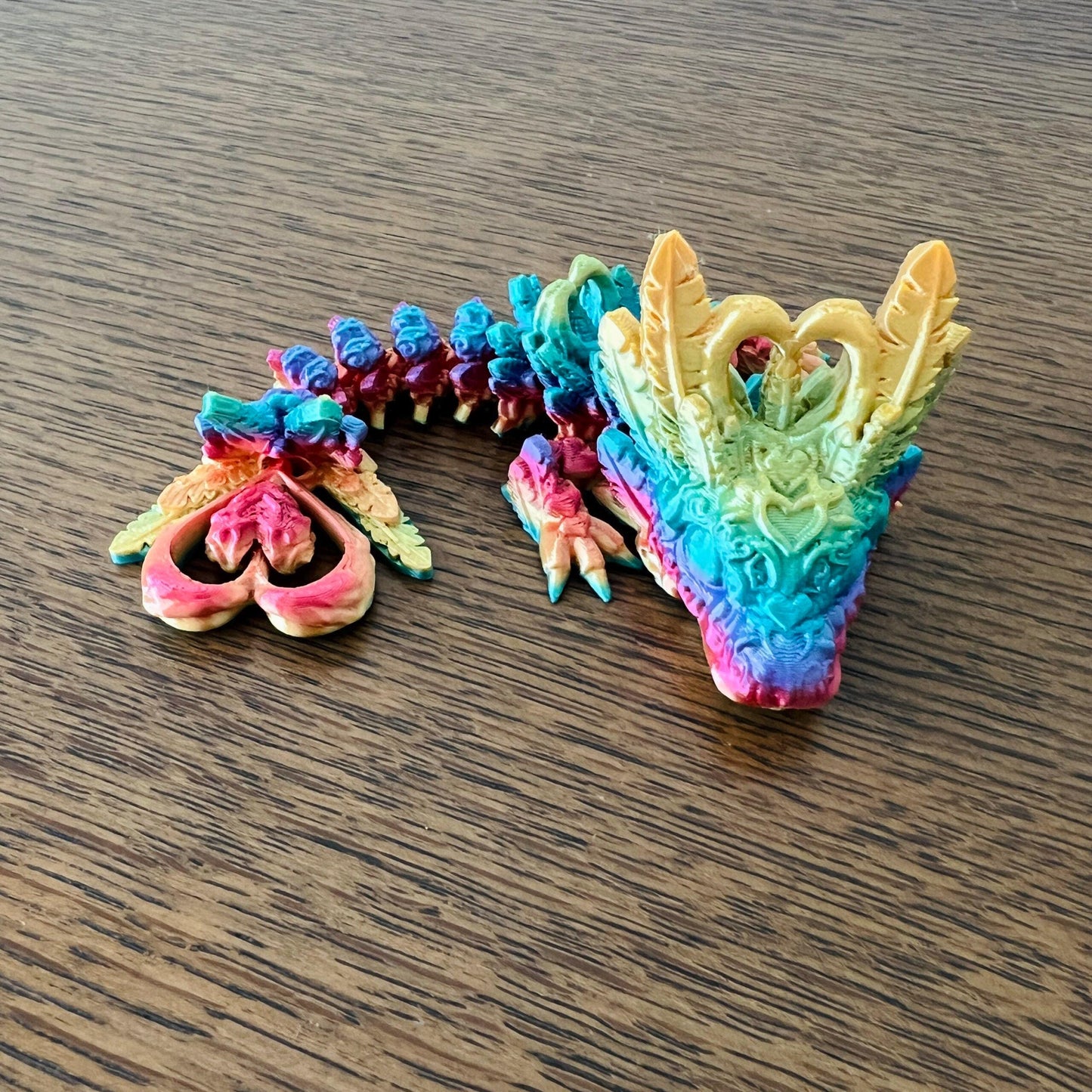 A colorful, articulated dragon with heart-themed details, perfect for sensory play and collection enhancement.