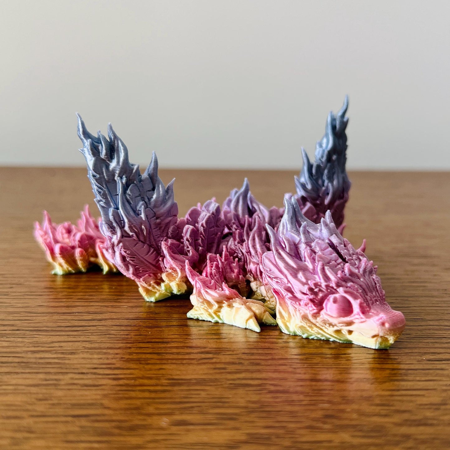 A vibrant phoenix dragon with fiery pink and blue details symbolizes rebirth, elegantly crafted to ignite your collection.
