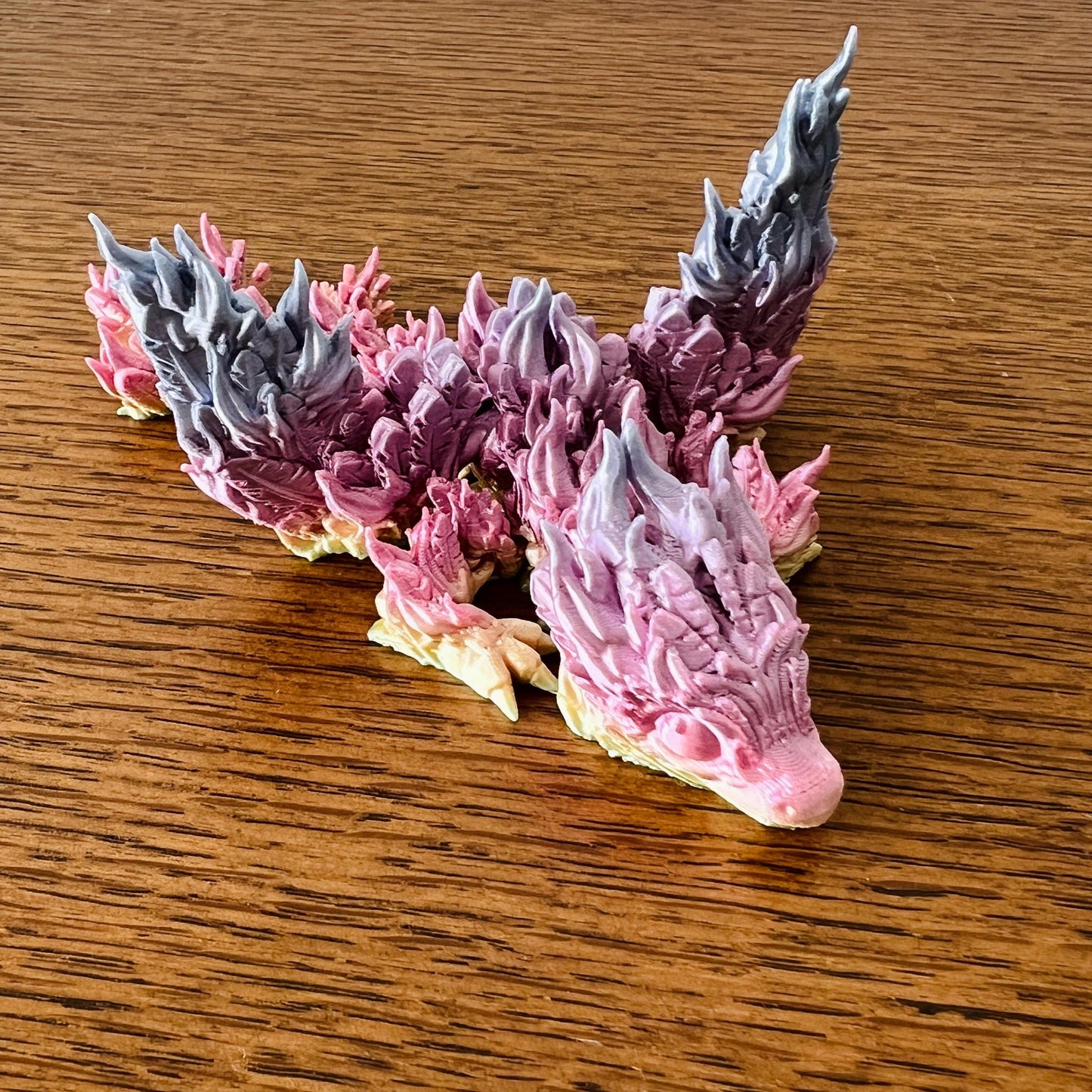 A vibrant Phoenix Dragon Tadling with fiery pink and gray details, symbolizing rebirth and resilience.
