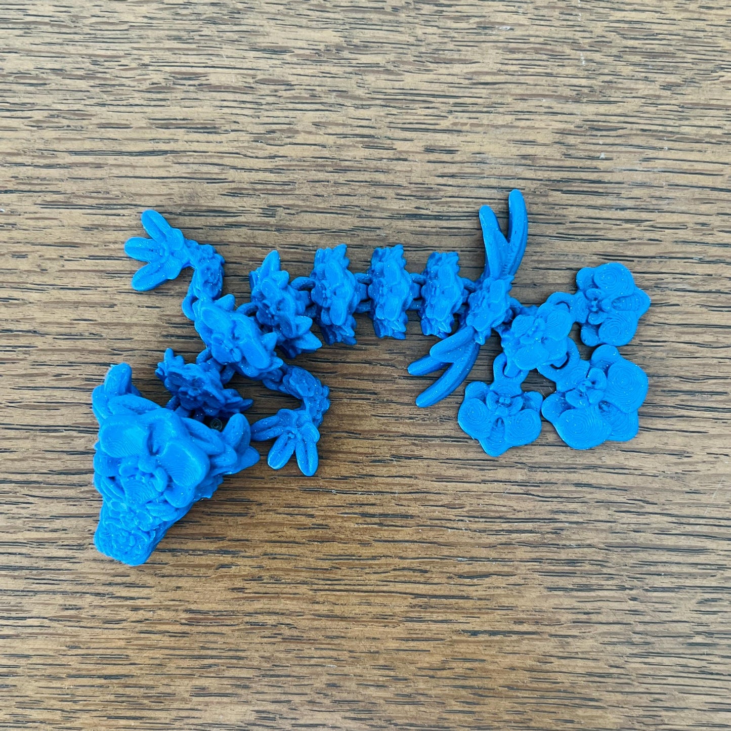 Whimsical blue dragon adorned with orchid-like details, showcasing intricate floral patterns and enchanting charm.