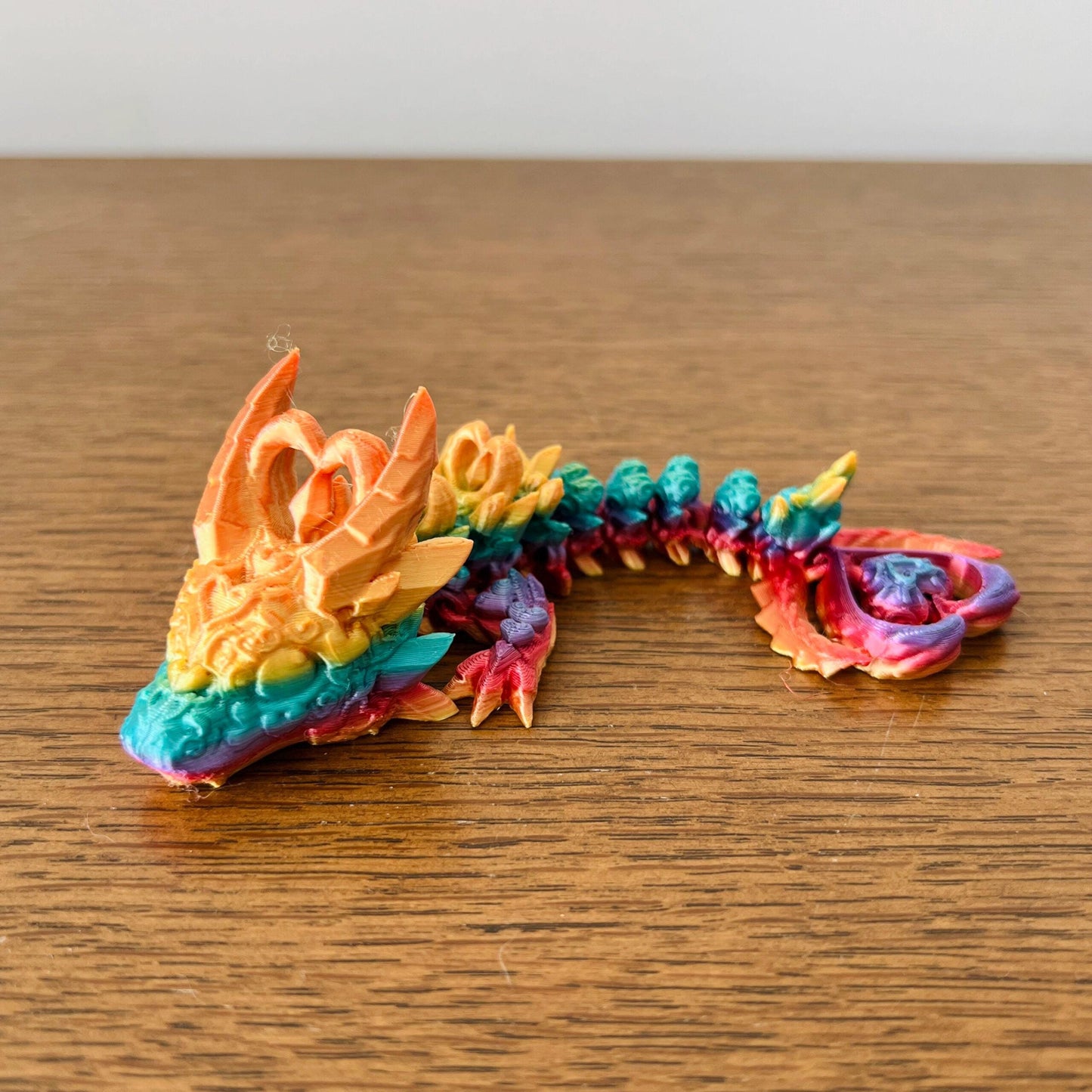 Colorful wingless dragon with intricate heart-shaped accents, showcasing a blend of vibrant hues and edgy elegance.