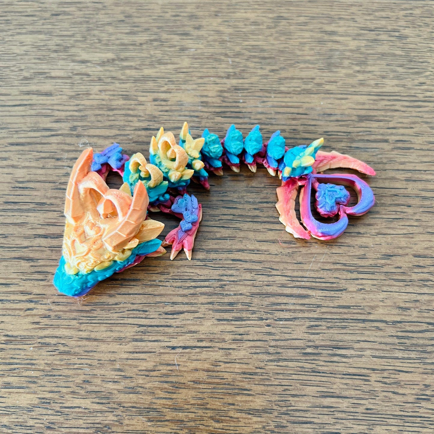 A wingless dragon with a dark, intricate design featuring heart-shaped accents in vibrant colors.
