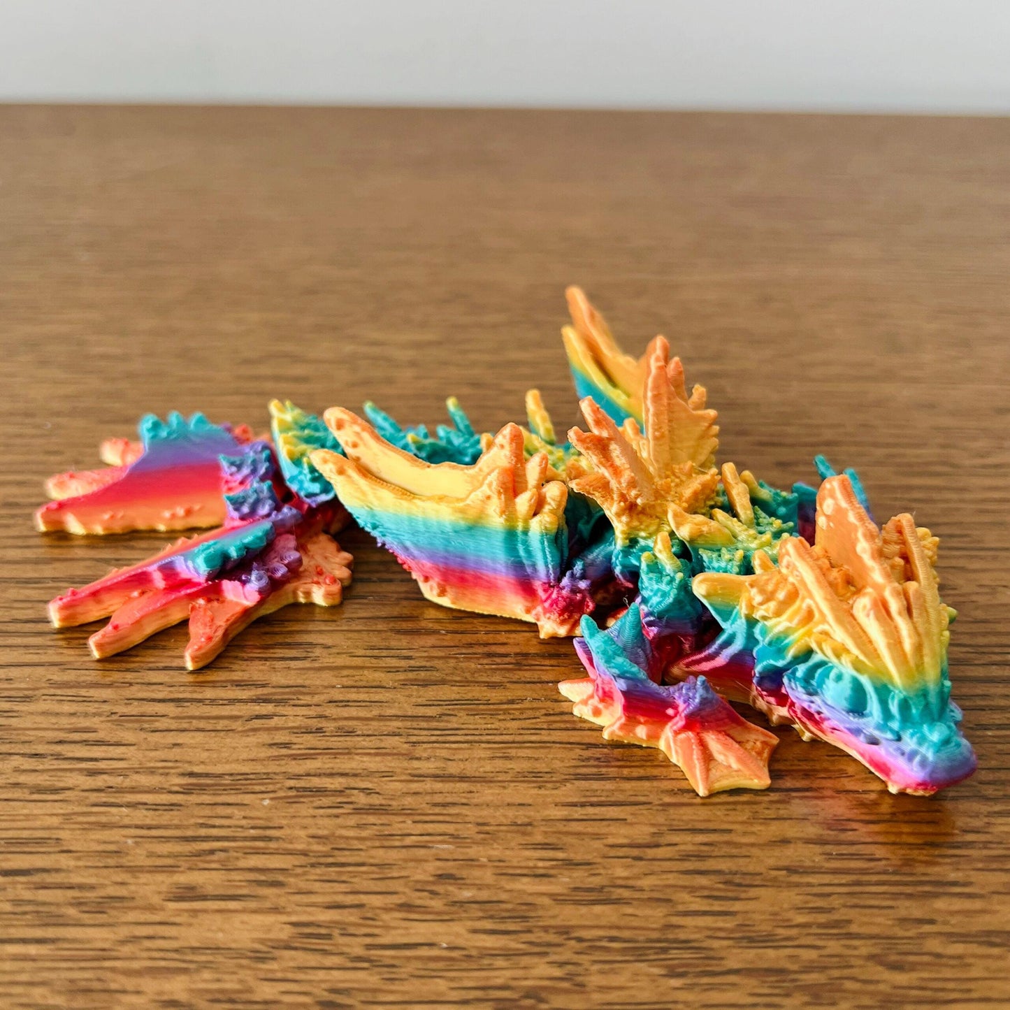 Colorful dragon with wave-inspired wings, blending vibrant hues of blue, orange, and pink for an aquatic feel.