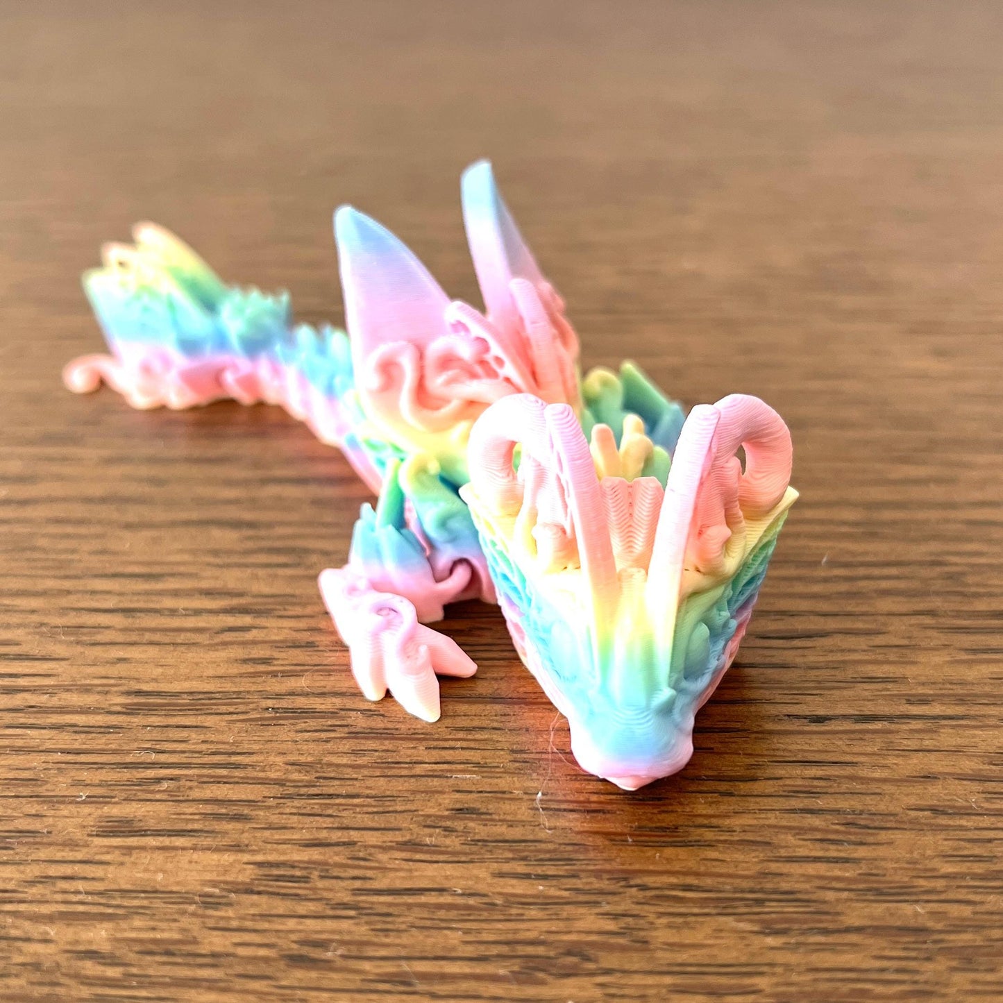 Colorful Mini Butterfly Dragon with intricate details, featuring delicate wings and a whimsical design, resting on a wooden s