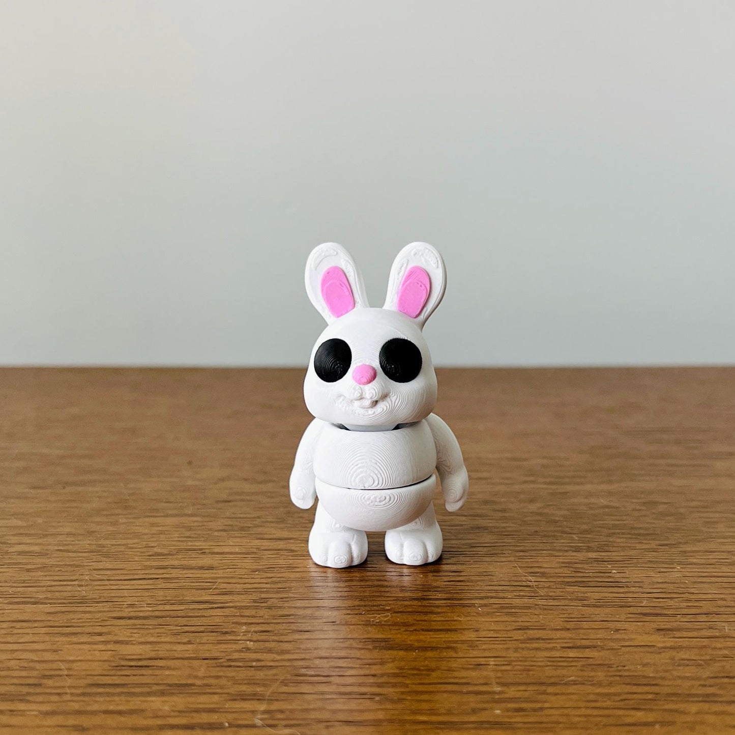Charming white bunny with pink ears and nose, standing on a wooden surface, perfect for sensory play and relaxation.