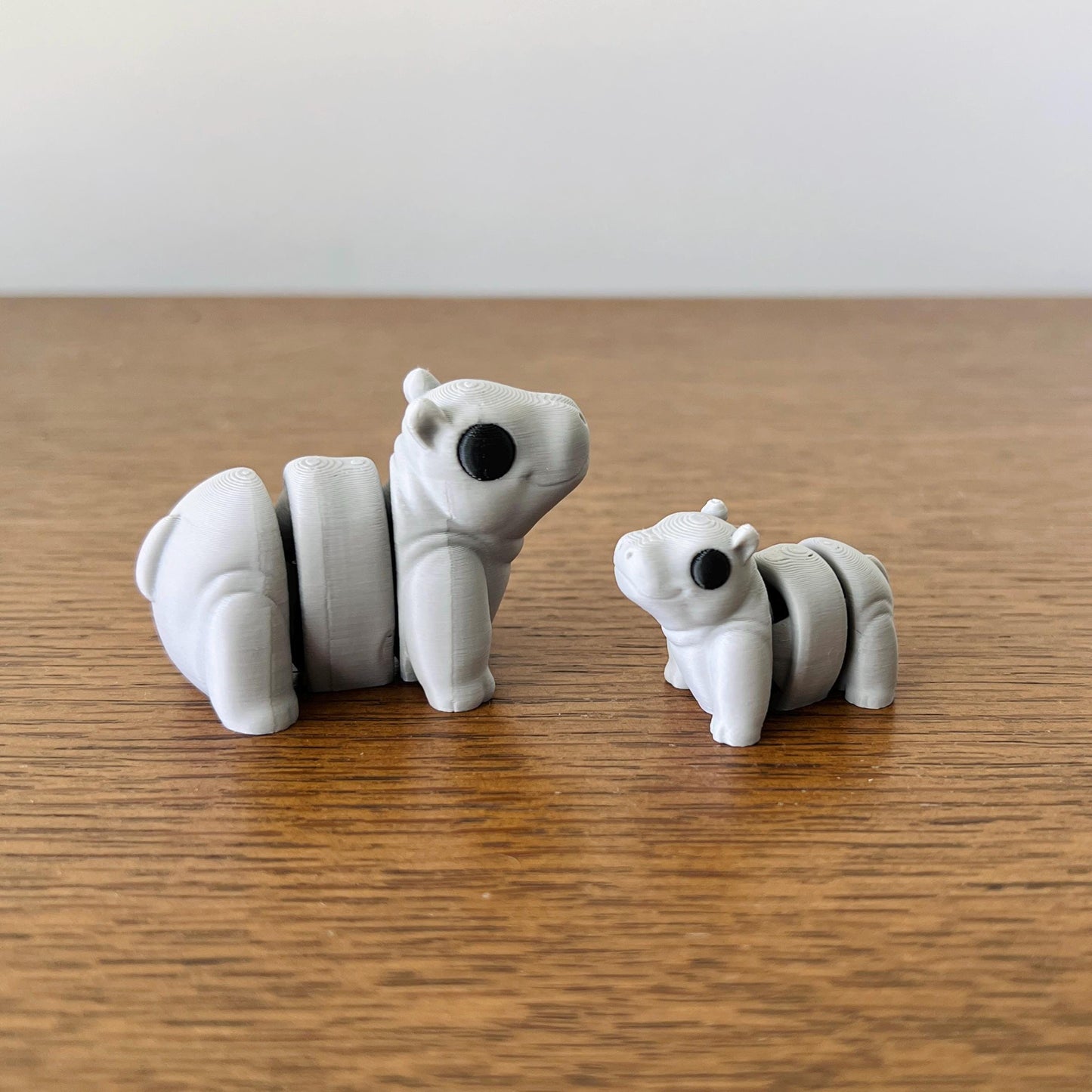 Two adorable, articulated mini hippos in soft gray with black eyes, perfect for sensory play and delightful collectibles.