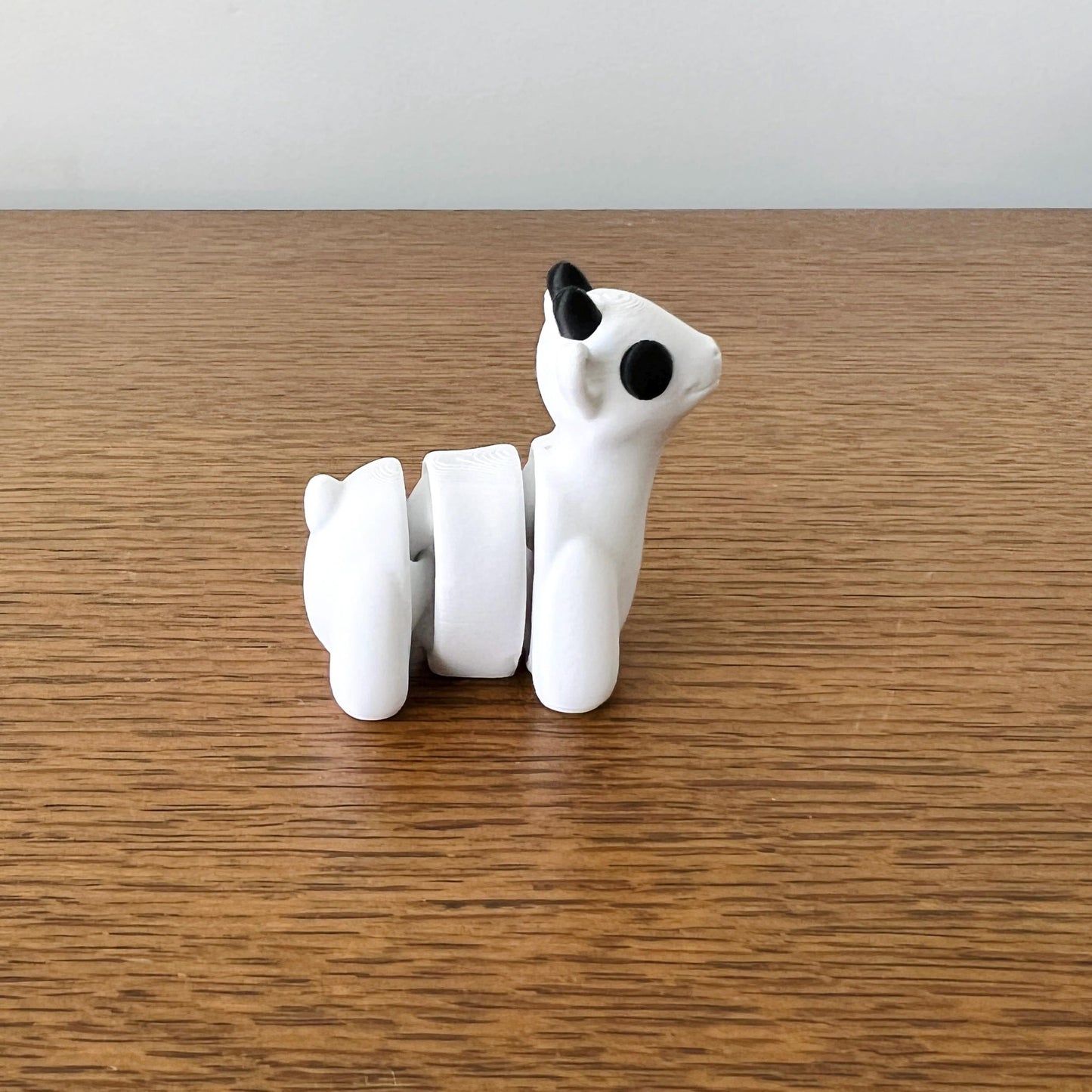 Charming 3D printed mini goat with flexible parts, featuring a white body and black accents, perfect for tactile fun.