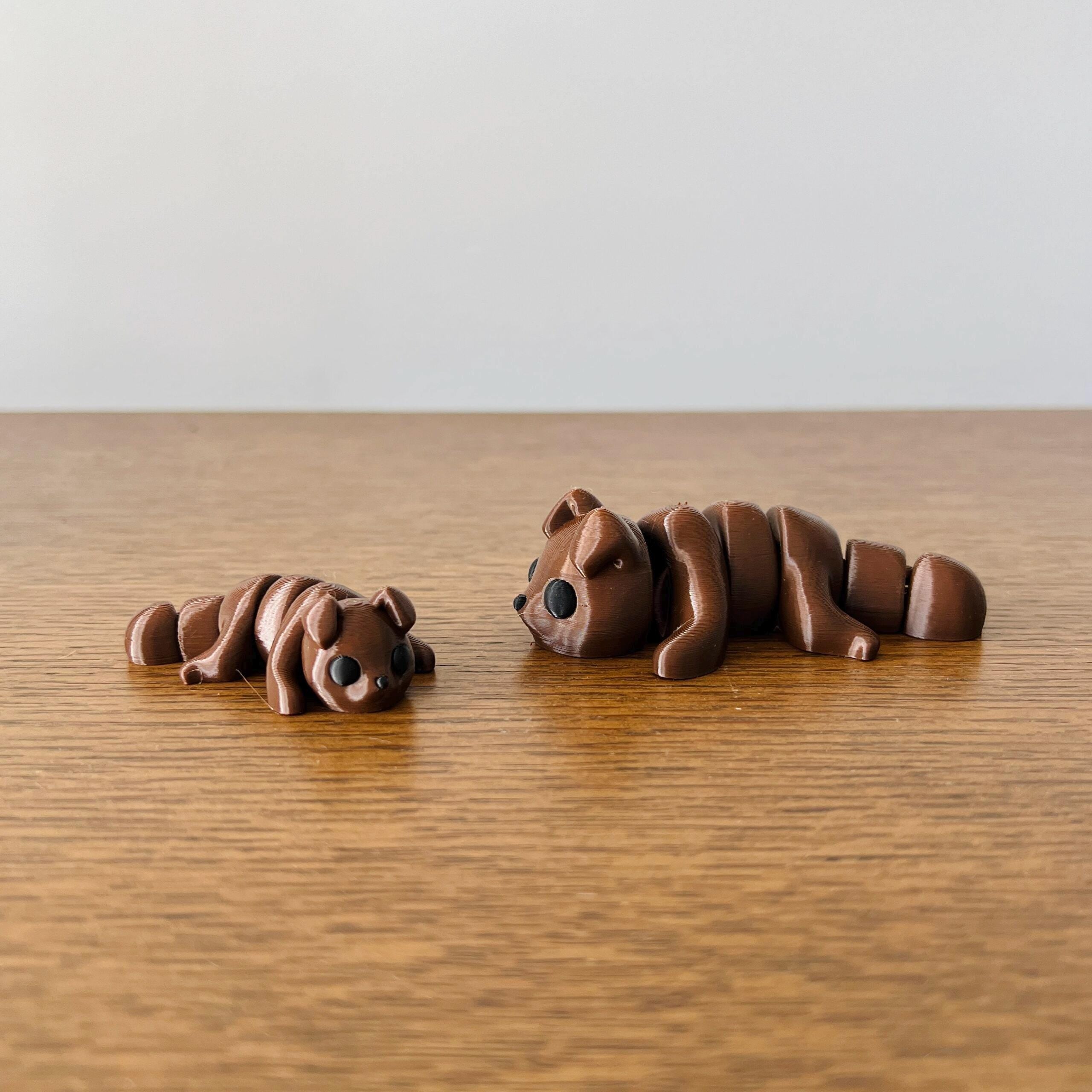 Adorable brown puppy figures, one large and one small, resting on a wooden surface with playful expressions.