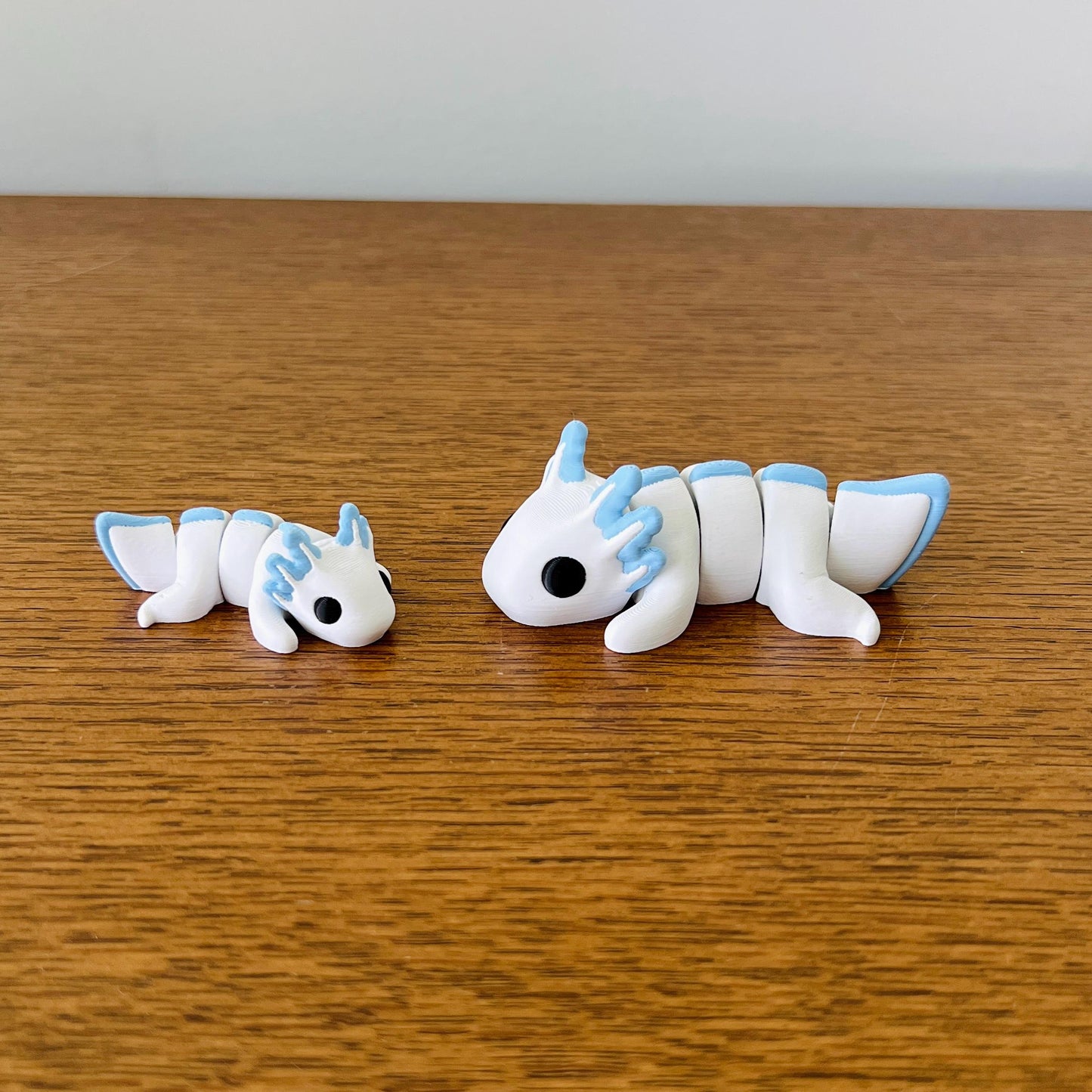Charming white axolotls with pastel blue accents, perfect for sensory play and delightful collecting.