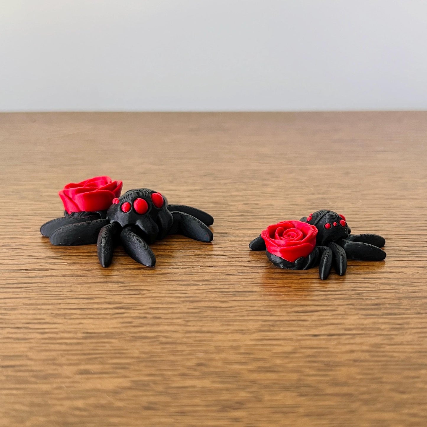 A charming black spider with red rose accents, blending gothic elegance and playful intrigue.