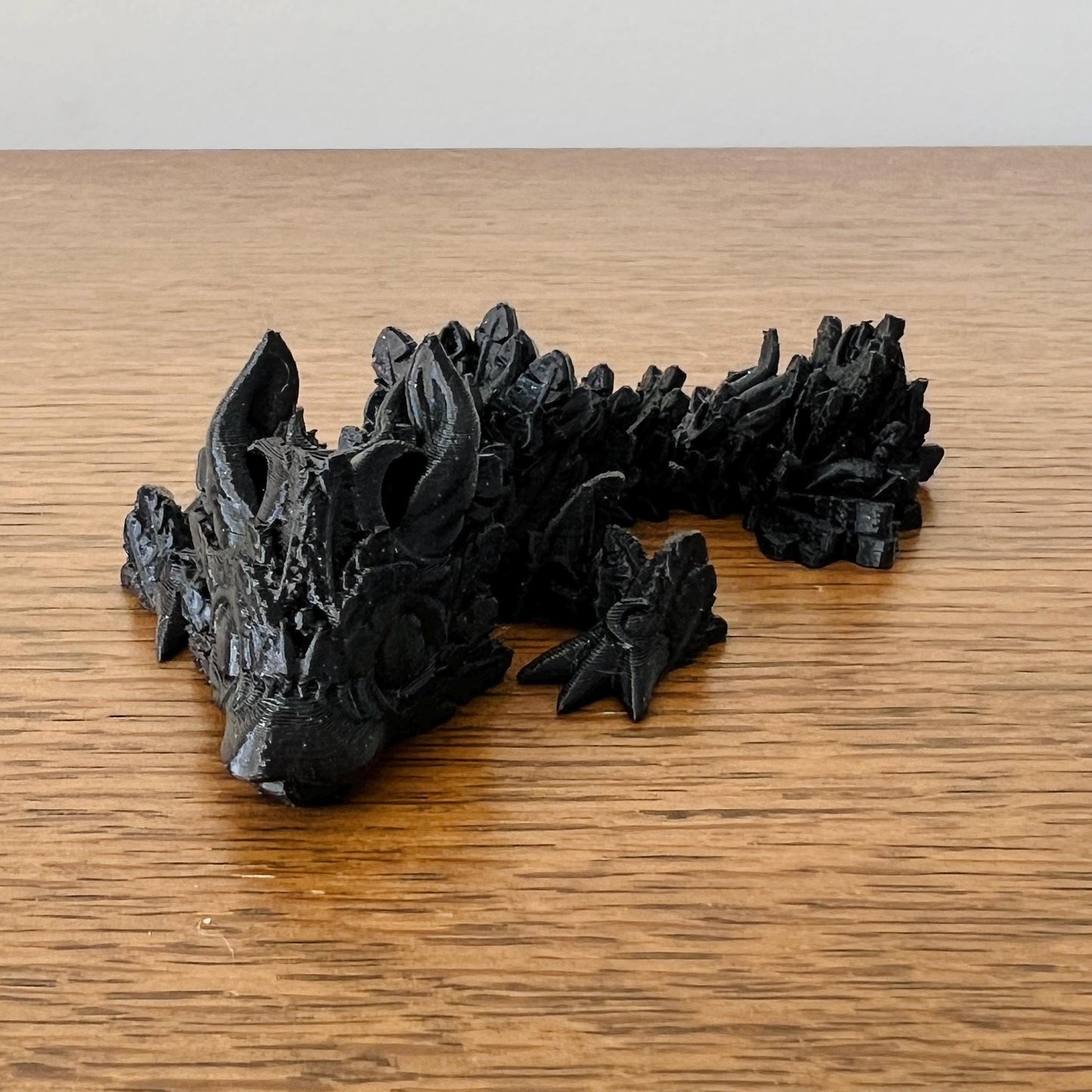 Petite black dragon with textured scales and pointed features, evoking the enchantment of the night sky.