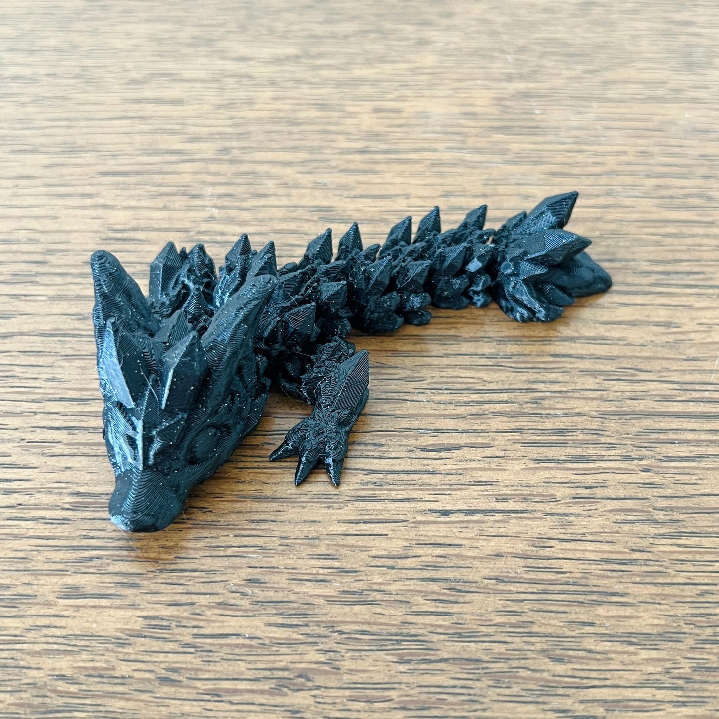 A black, intricately detailed creature blends wolf and dragon features, showcasing sharp spikes and a fierce expression.