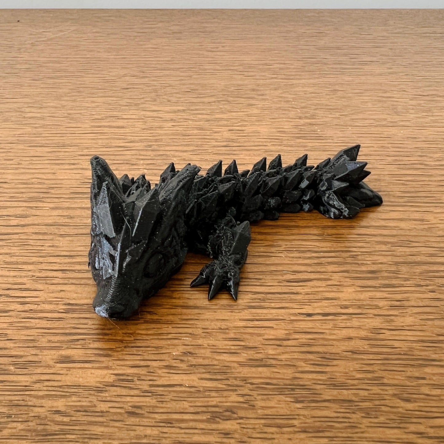 Mini Wolf Dragon Tadling features intricate black detailing with a spiky body and fierce expression, embodying strength and m