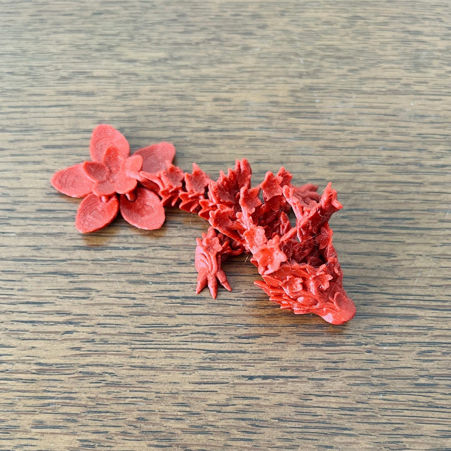 Delicate red dragon intertwined with a cherry blossom, showcasing intricate floral details and a whimsical spring essence.