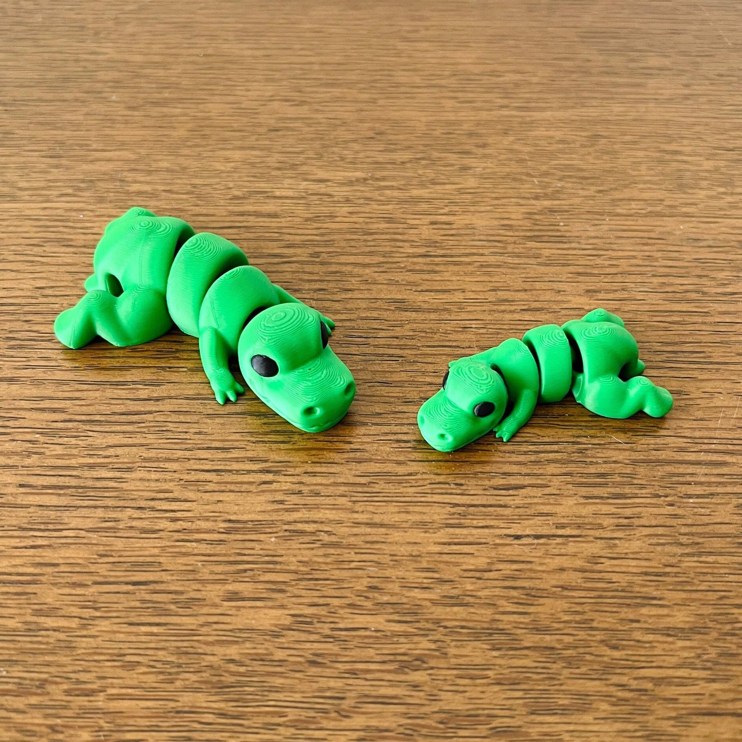 Two vibrant green miniature T-Rex figures with intricate details, showcasing their playful and dynamic poses.