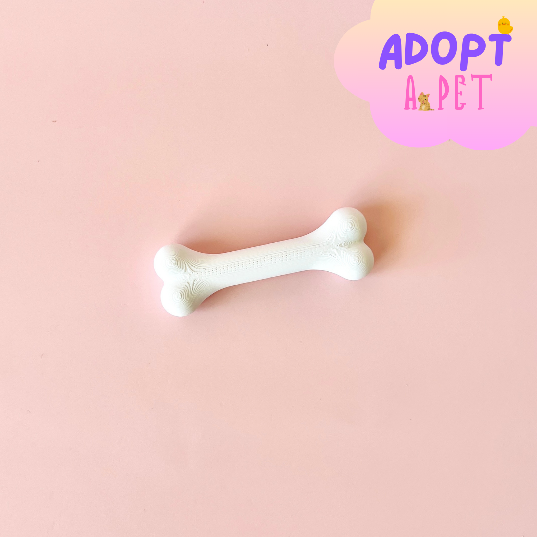 White bone-shaped object on a soft pink background with a playful "ADOPT A PET" graphic in the corner.