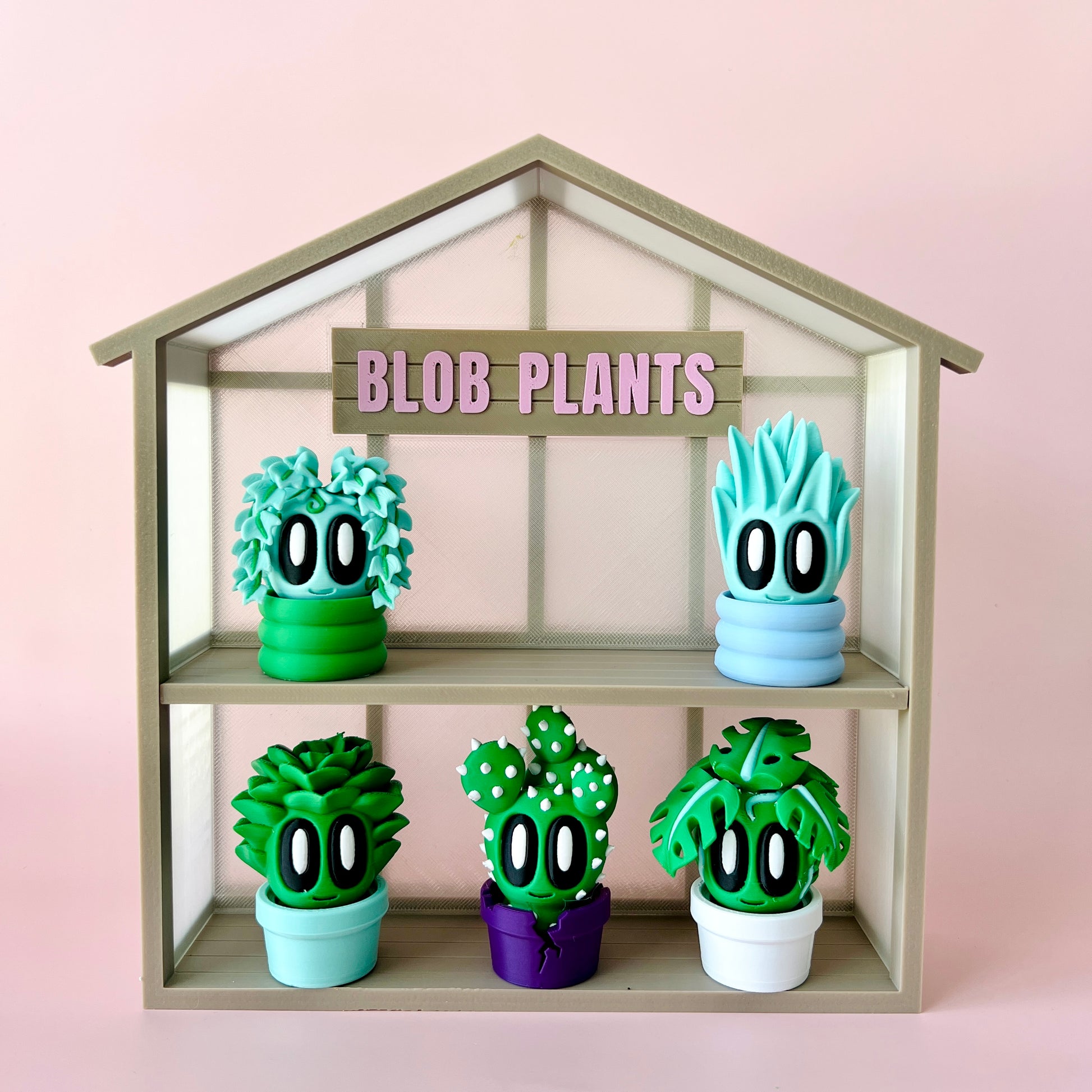 Colorful, cartoonish plant figures displayed in a house-shaped shelf, featuring oversized eyes and playful designs.