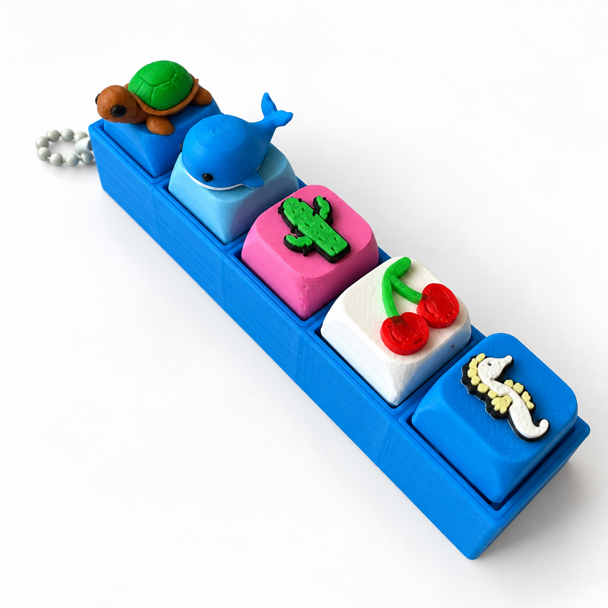5 Key Fidget Clicker, 3D printed fidget clicker in blue with turtle, whale, cactus, cherry and seahorse keycaps, angled view