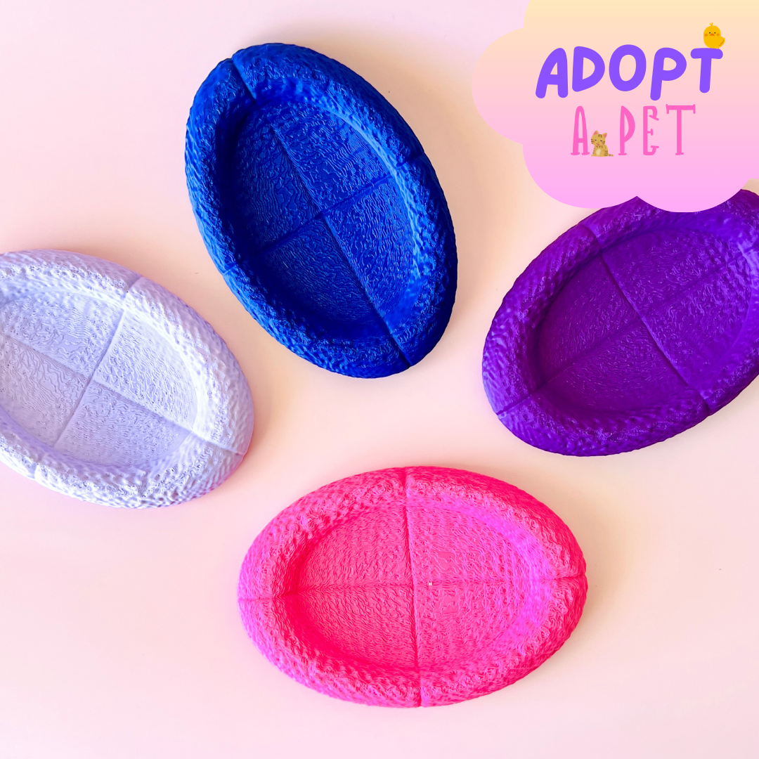 Colorful oval-shaped dishes in shades of pink, purple, blue, and lavender arranged on a soft background.