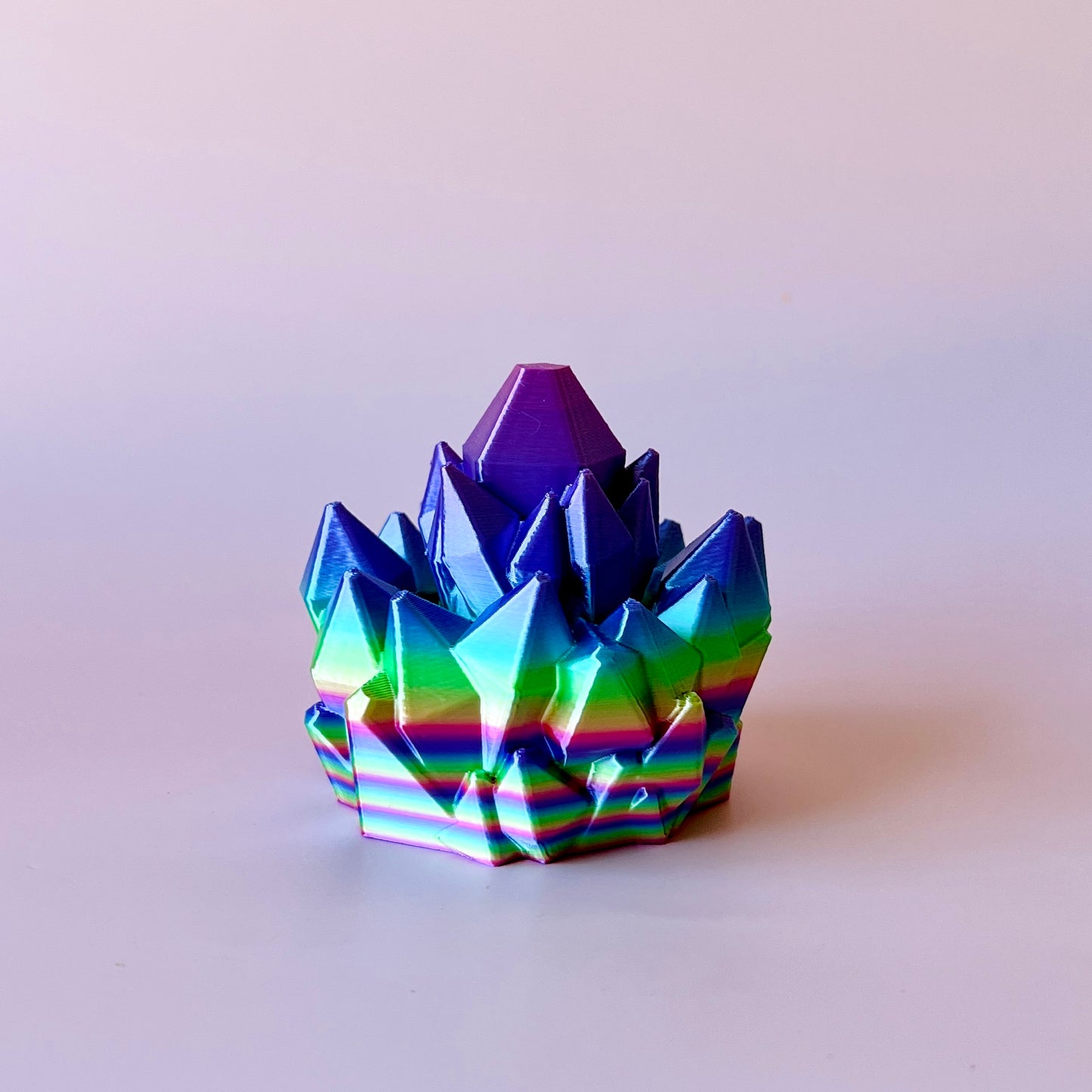 A vibrant, multi-colored crystal-like structure with sharp peaks and a smooth base, reflecting light beautifully.