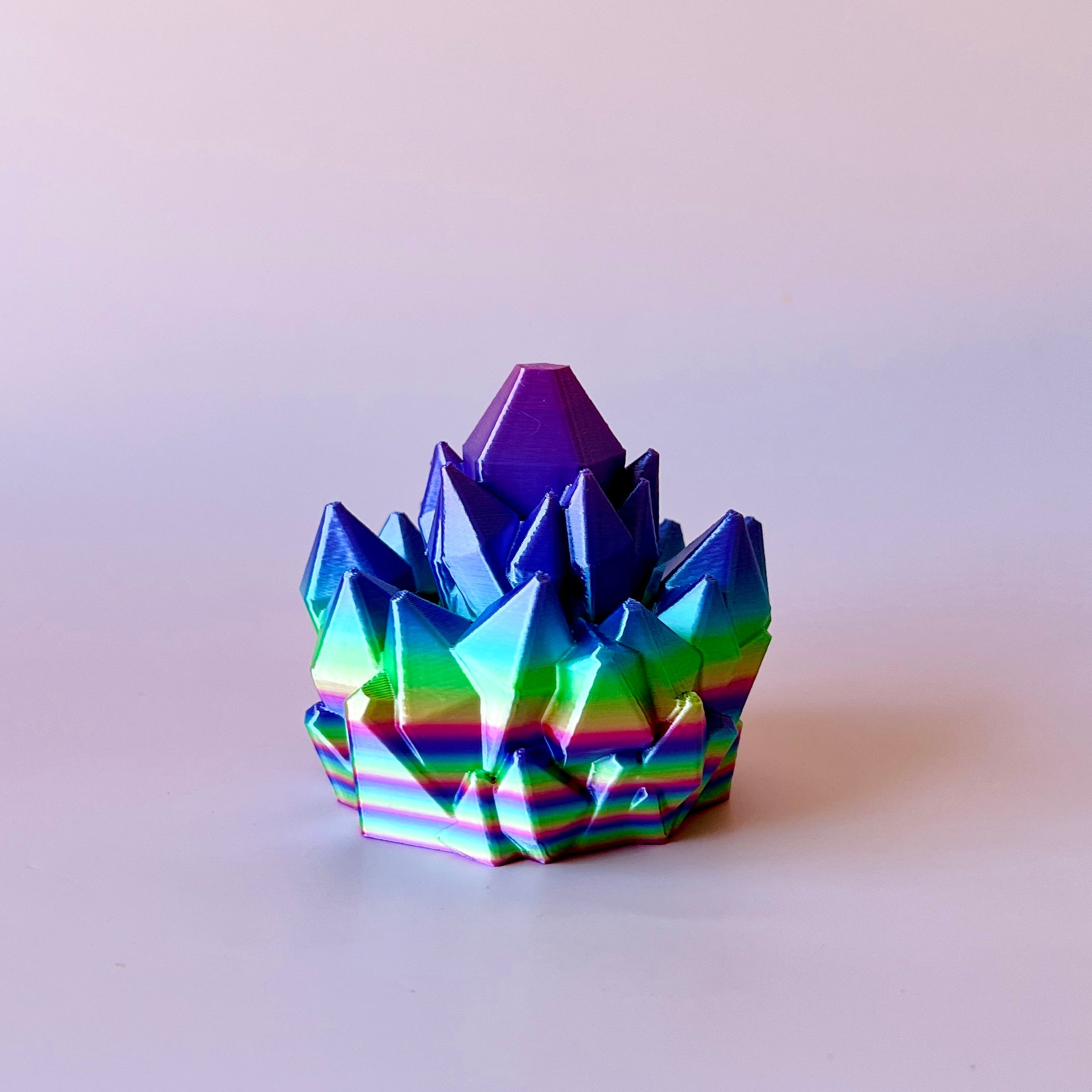 A vibrant, multi-colored crystal-like structure with sharp peaks and a smooth base, reflecting light beautifully.