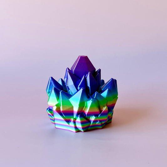 A vibrant, multi-colored crystal-like structure with sharp peaks and a smooth base, reflecting light beautifully.