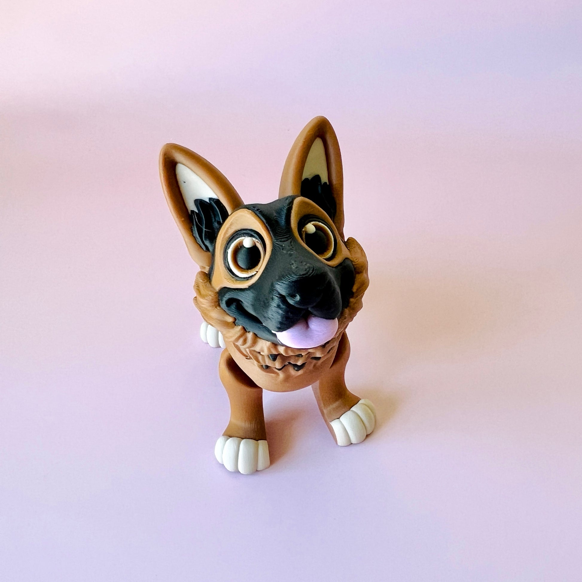 A cheerful German Shepherd figure with large eyes, floppy ears, and a playful stance against a pink background.