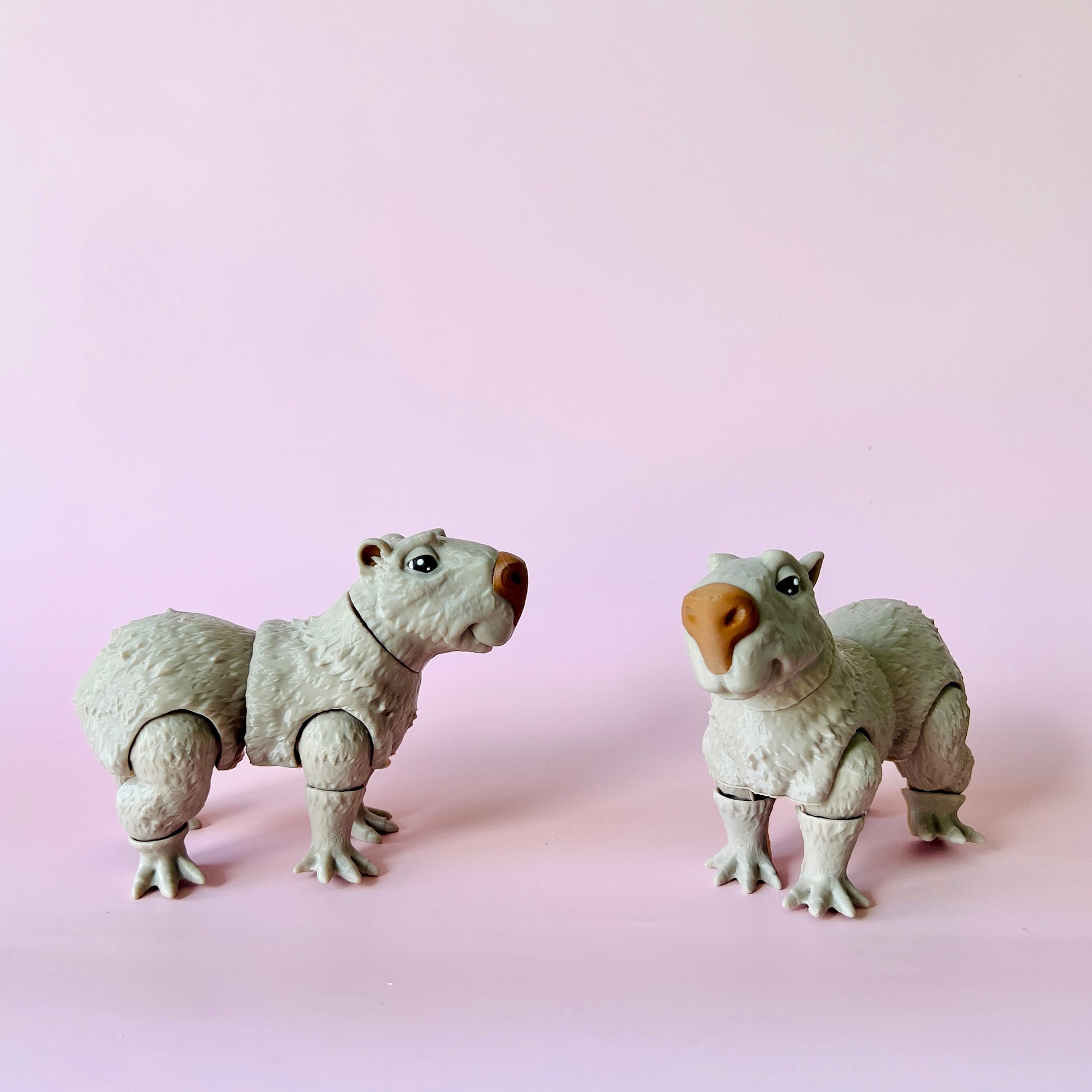 Two cute, white, furry creatures with expressive eyes on a soft pink background.