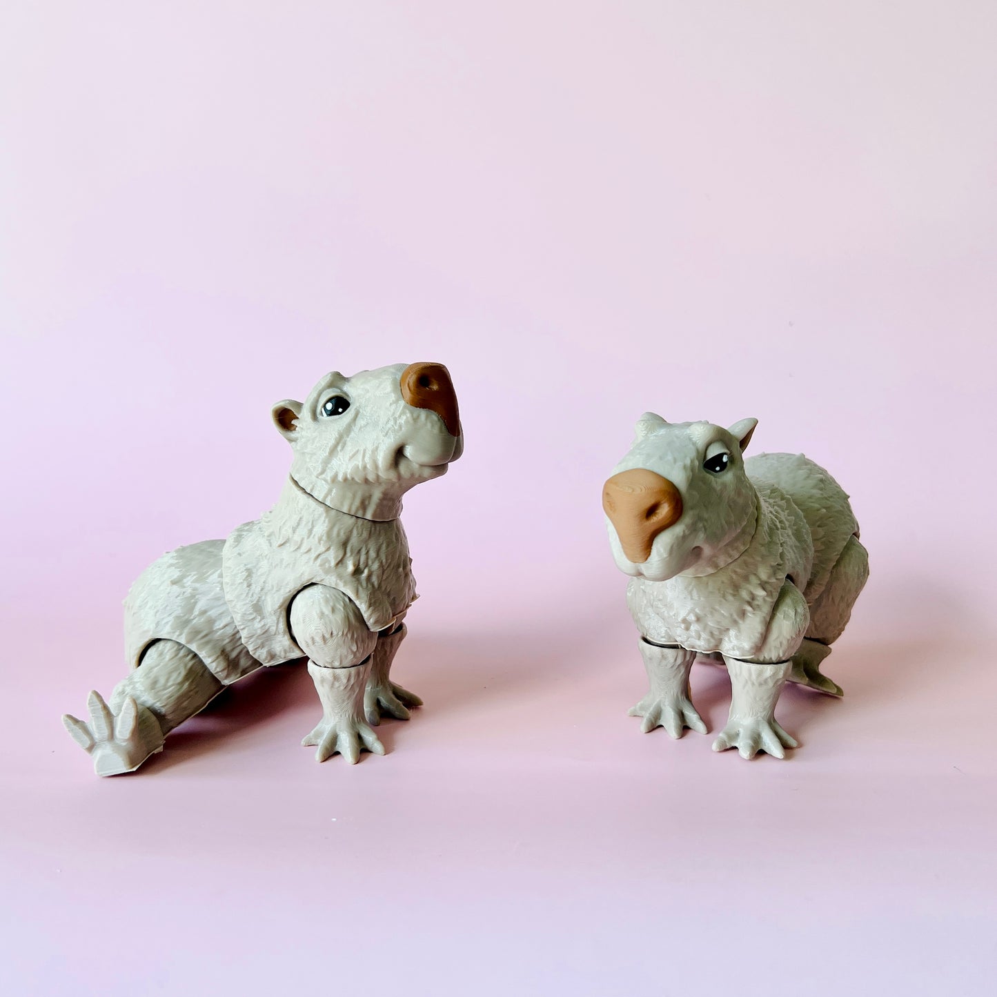 Two whimsical, white creatures with adorable expressions posed against a soft pink background.
