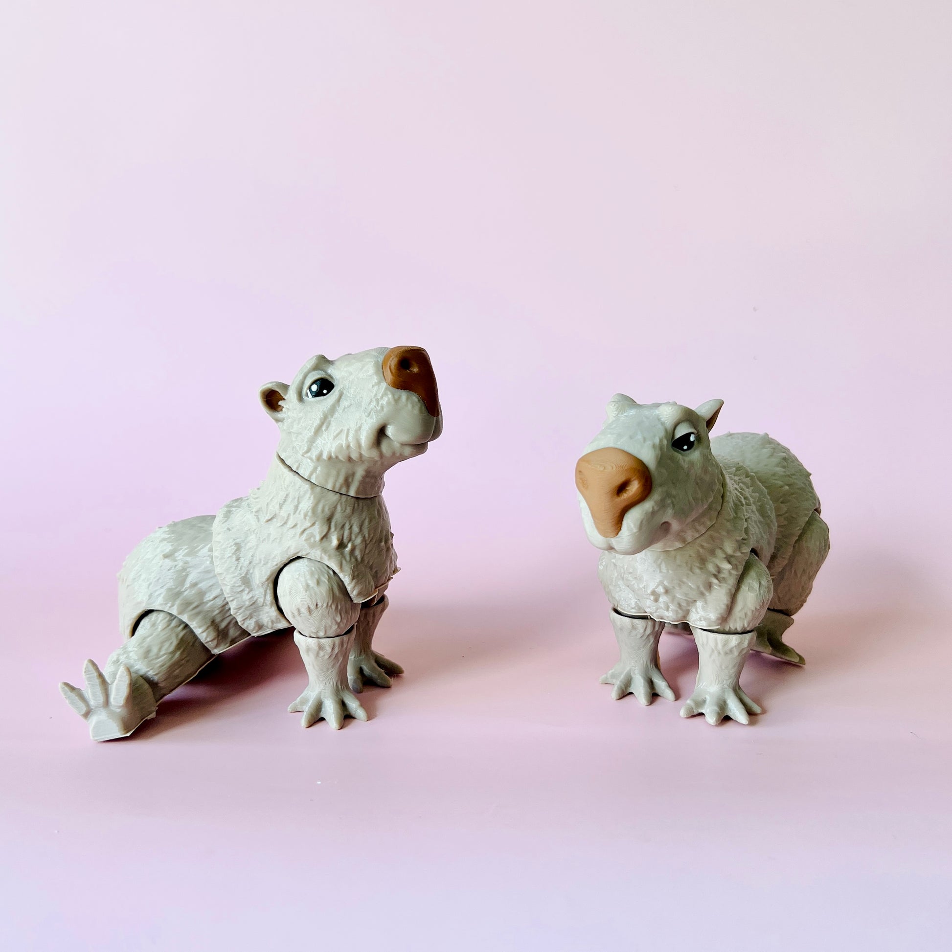 Two whimsical, white creatures with adorable expressions posed against a soft pink background.