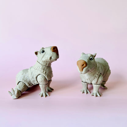Two whimsical, white creatures with adorable expressions posed against a soft pink background.