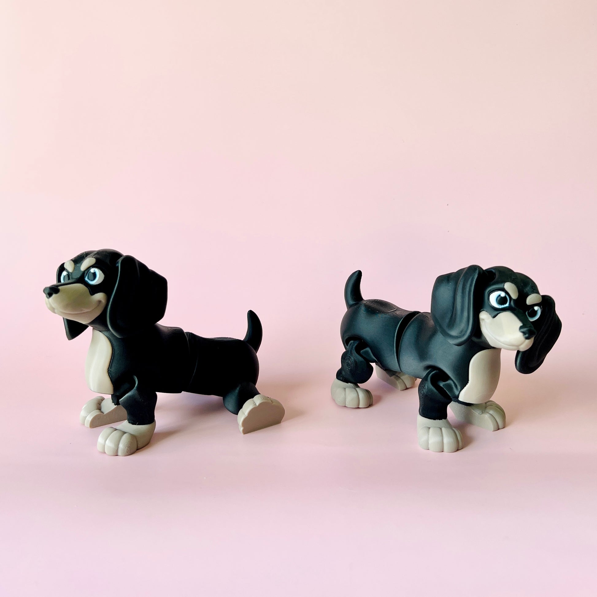 Two playful black and white dog figures with expressive eyes, set against a soft pink background.