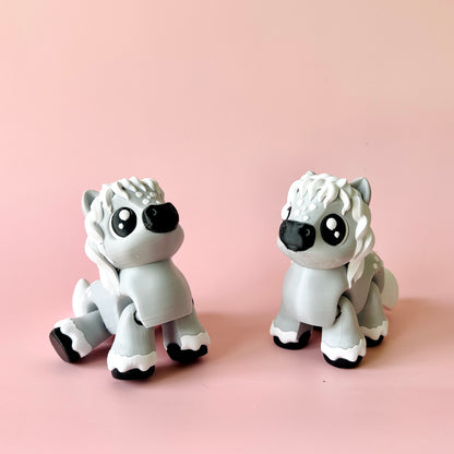 Two cute gray figurines resembling fluffy animals with large eyes, set against a soft pink background.