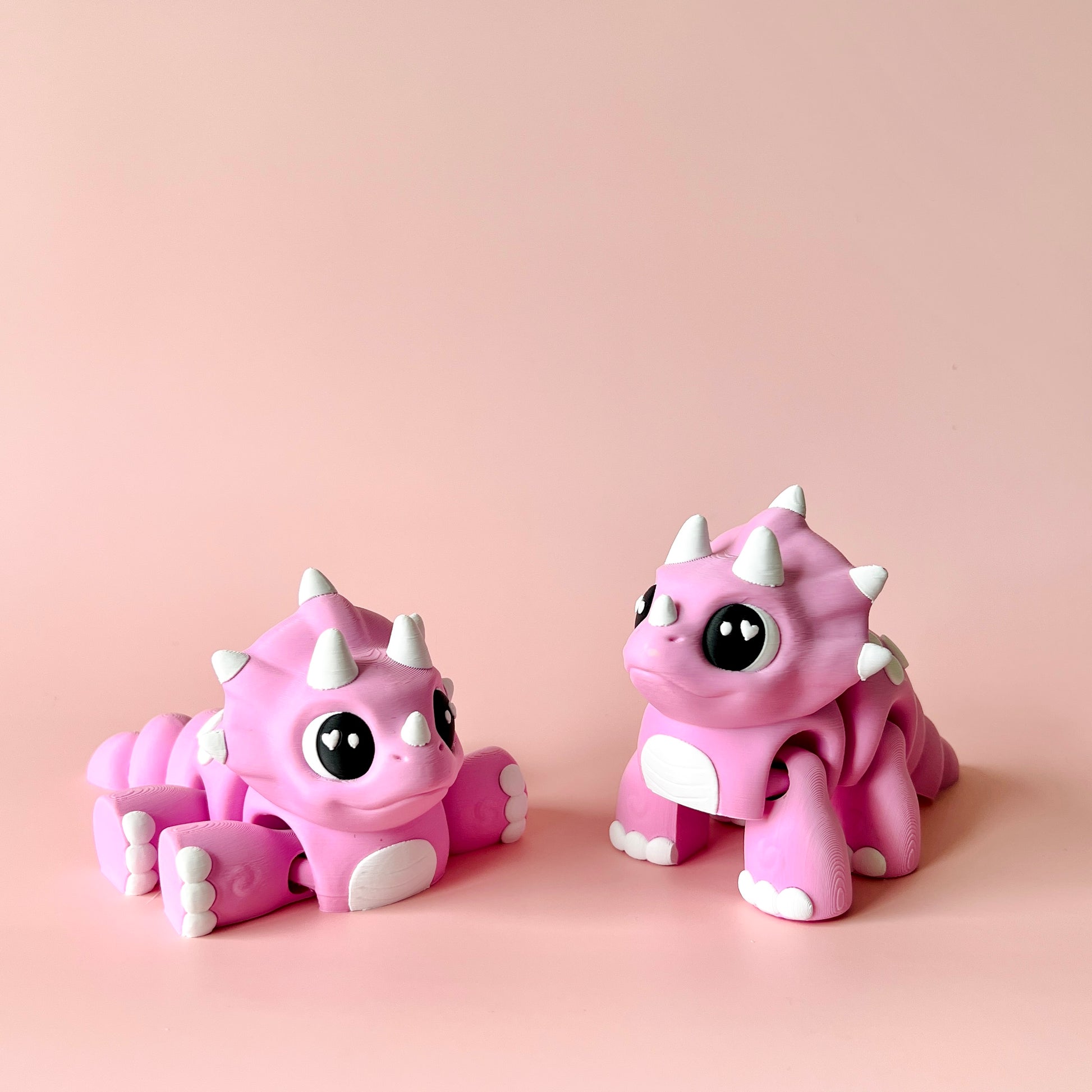 Two cute pink creatures with large eyes and white spikes, set against a soft pink background.