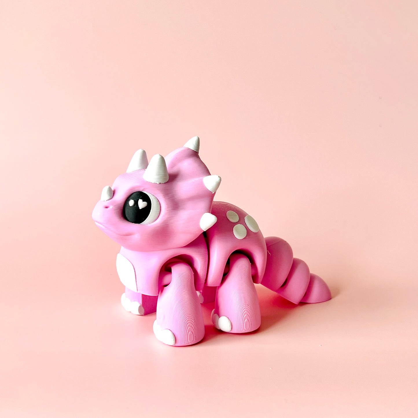 A cute pink creature with spikes and big eyes, set against a soft pink background, exuding a whimsical charm.