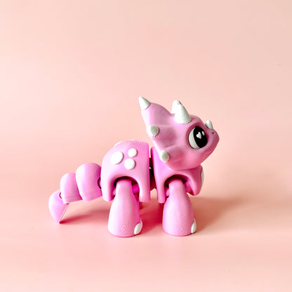 A cute pink creature with spikes and large eyes, set against a soft pink background.