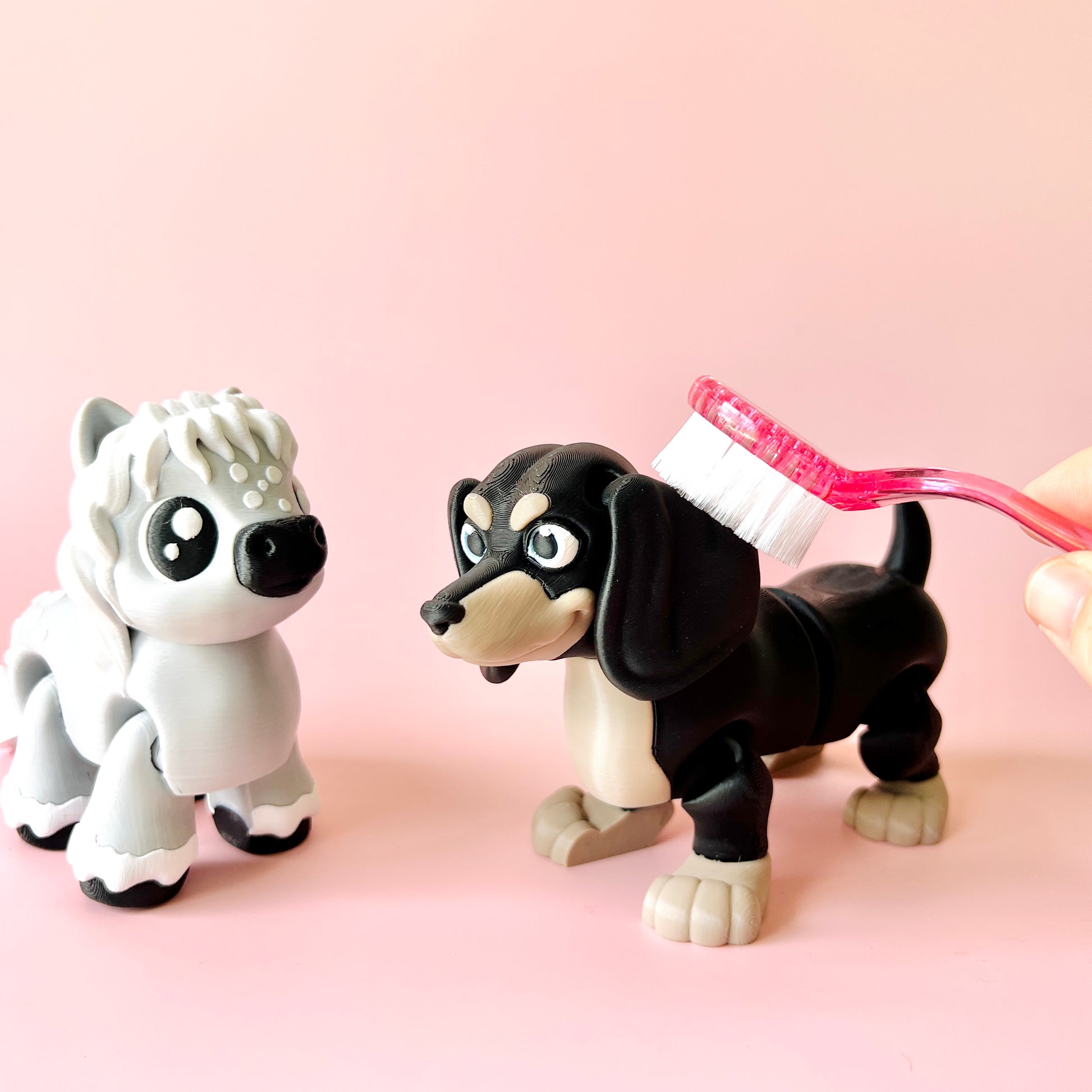 Two playful animal figures, one gray with white fur and the other black with tan accents, being brushed with a pink toothbrus