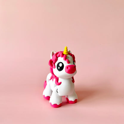 A whimsical unicorn figure with pink mane and a golden horn stands against a soft pink background.