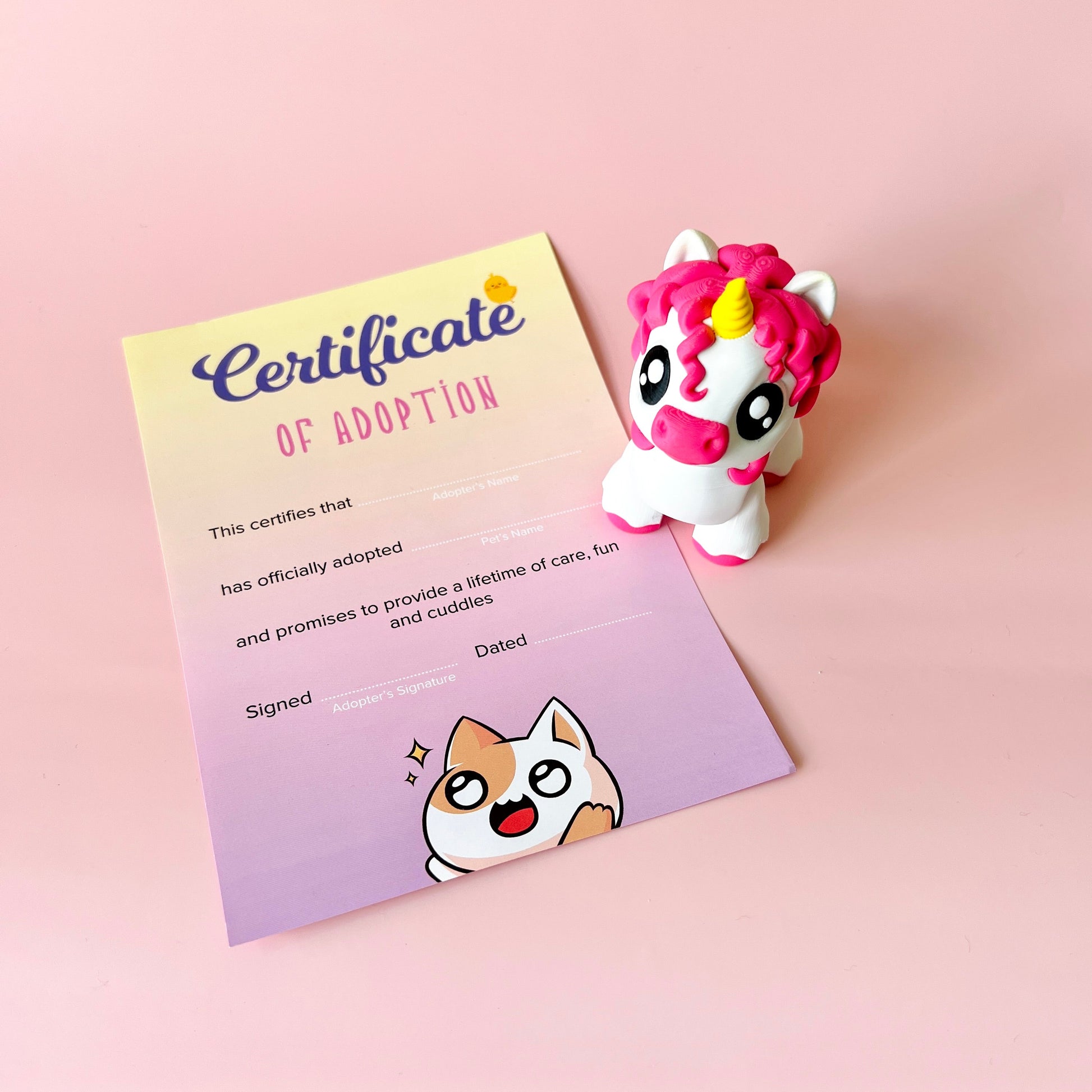 A colorful adoption certificate alongside a cute unicorn figurine, set against a soft pink background.