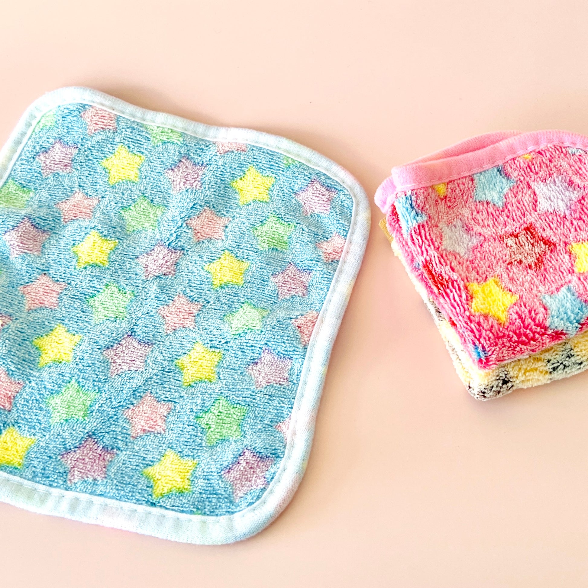 Colorful star-patterned cloths in pastel shades, with a blue cloth featuring yellow and pink stars alongside a pink one.