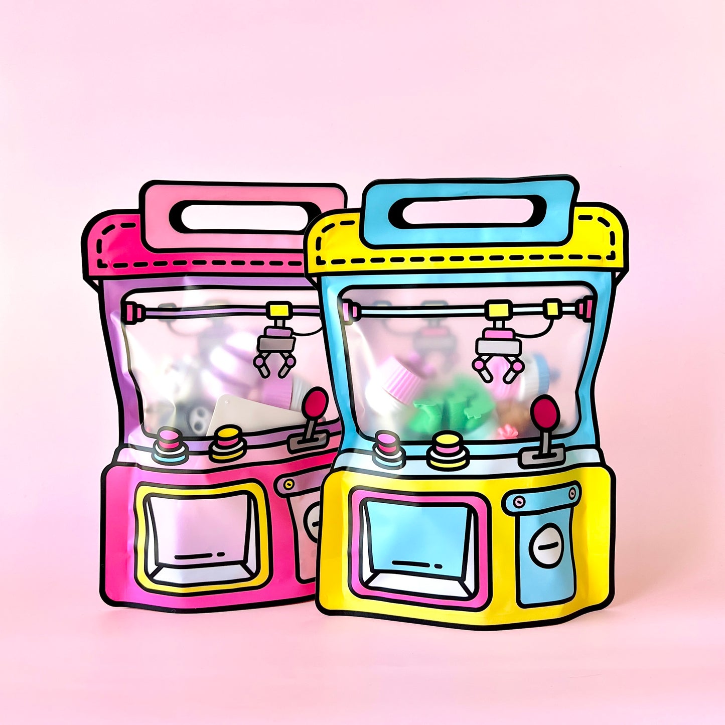 Two colorful claw machines in pink and yellow against a soft pink background, featuring playful, vibrant details inside.