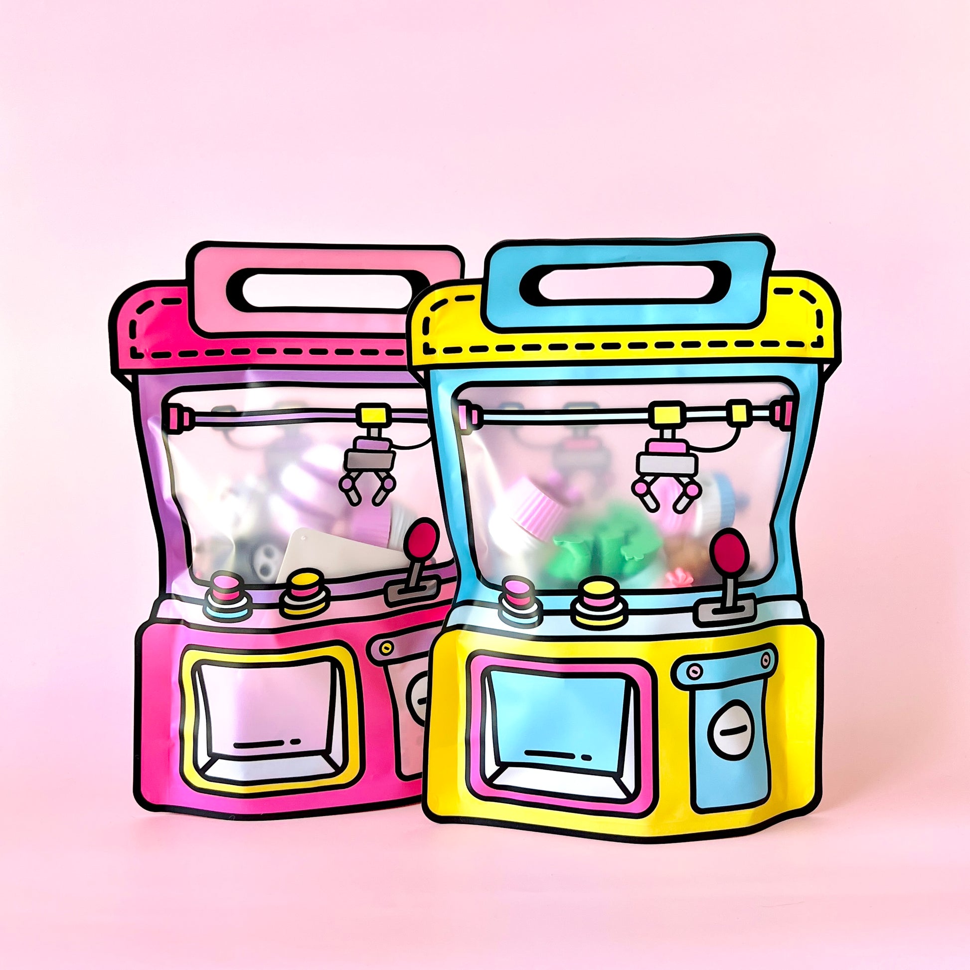 Two colorful claw machines in pink and yellow against a soft pink background, featuring playful, vibrant details inside.