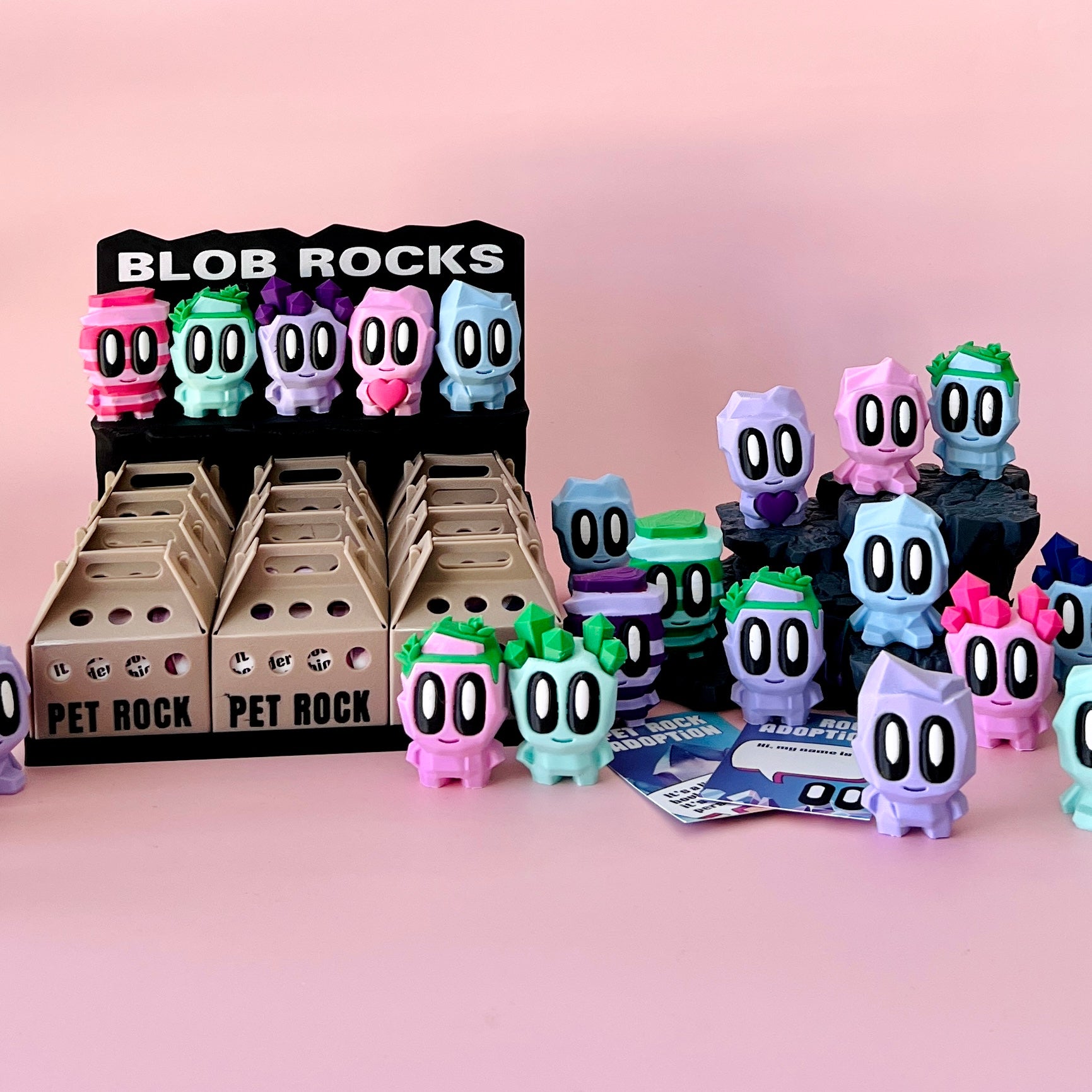 A colorful display of whimsical figures with large eyes, set against a soft pink background.